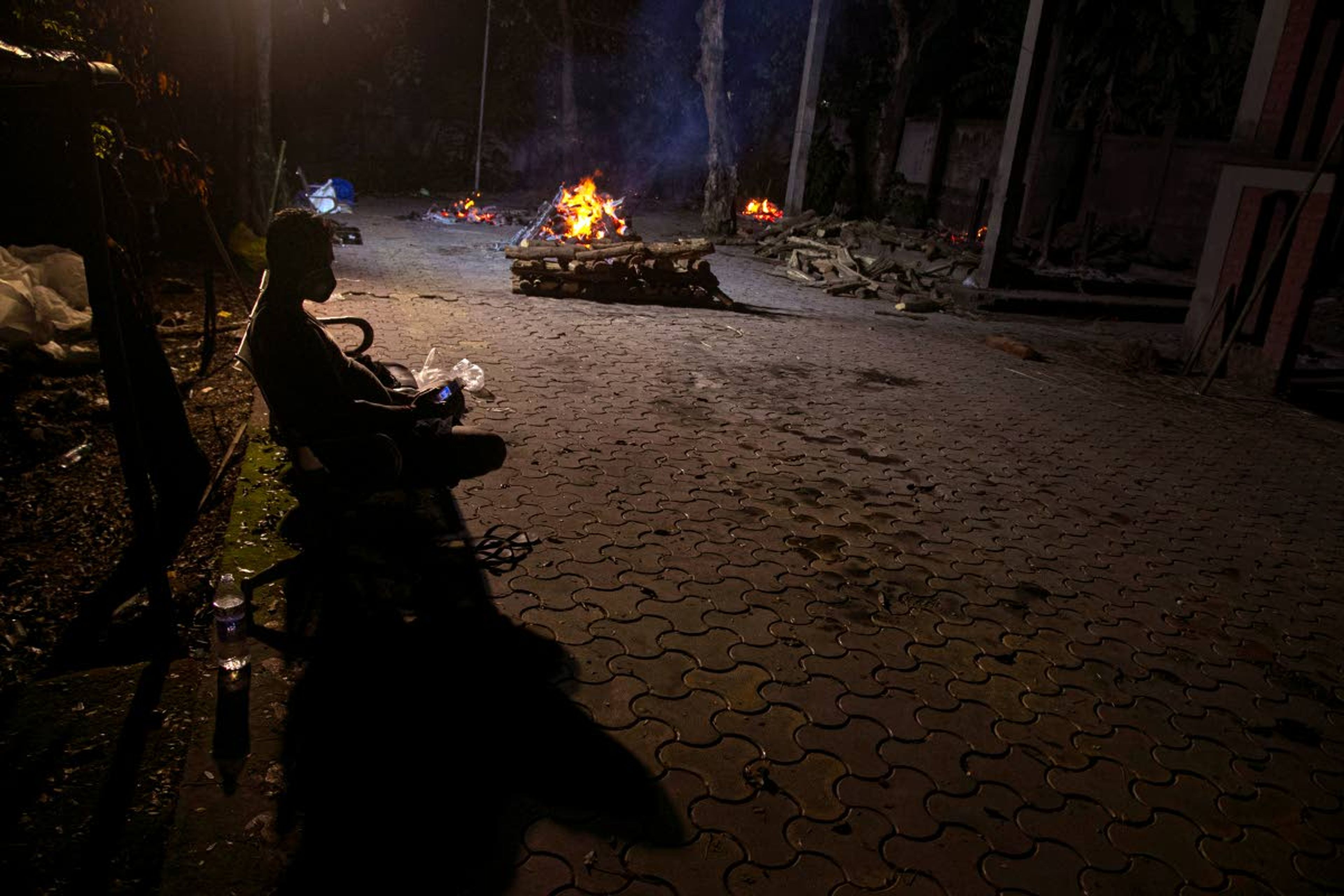 Ramananda Sarkar, 43, checks his mobile phone in between cremating bodies of COVID-19 victims on Sept. 15 in Gauhati, India.