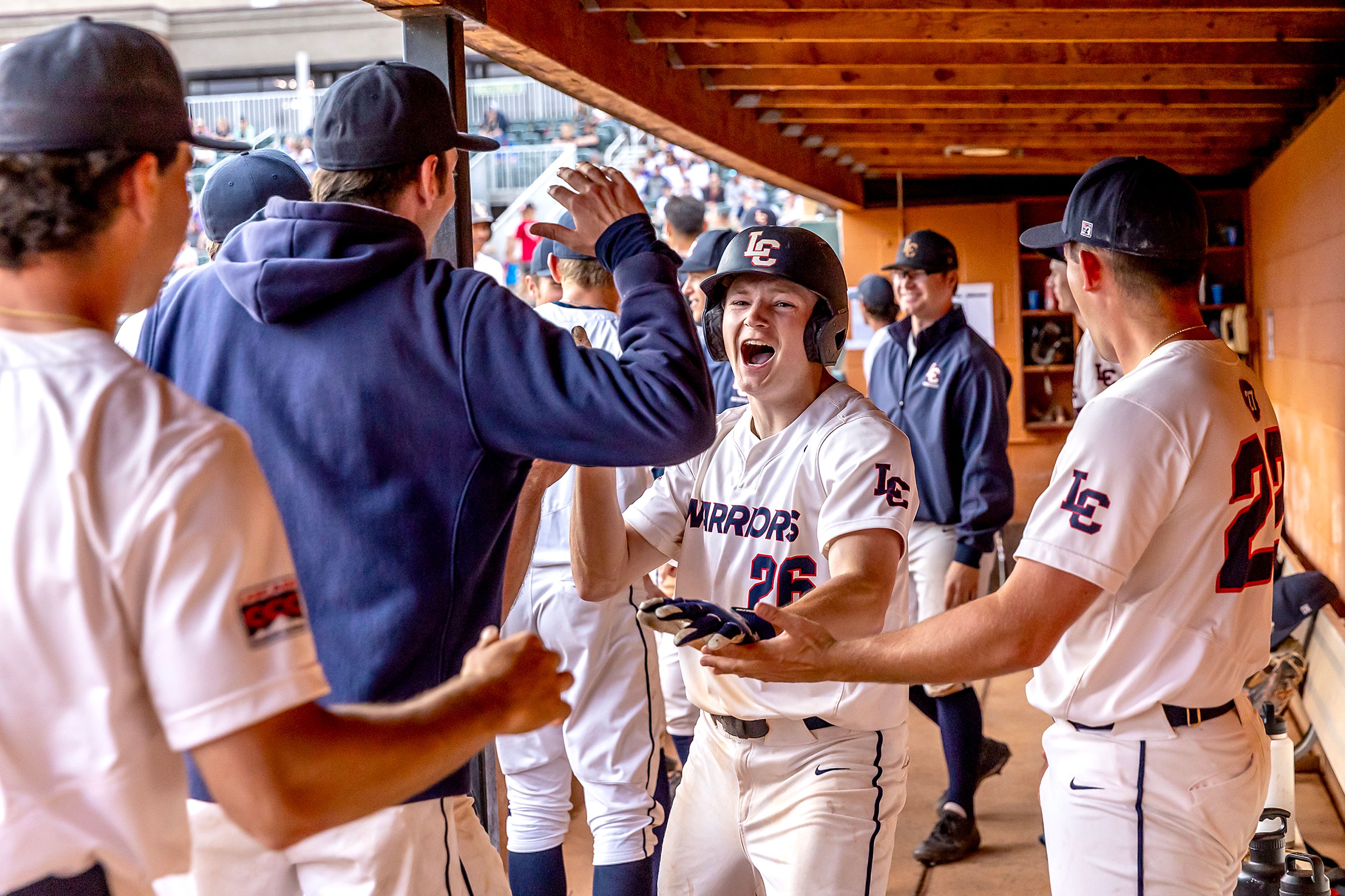 Lewis-Clark State's Jake Gish slaps hands with teammates as he comes through the dugout after hitting a home run against UBC during the NAIA Opening Round on Monday at Harris Field in Lewiston.