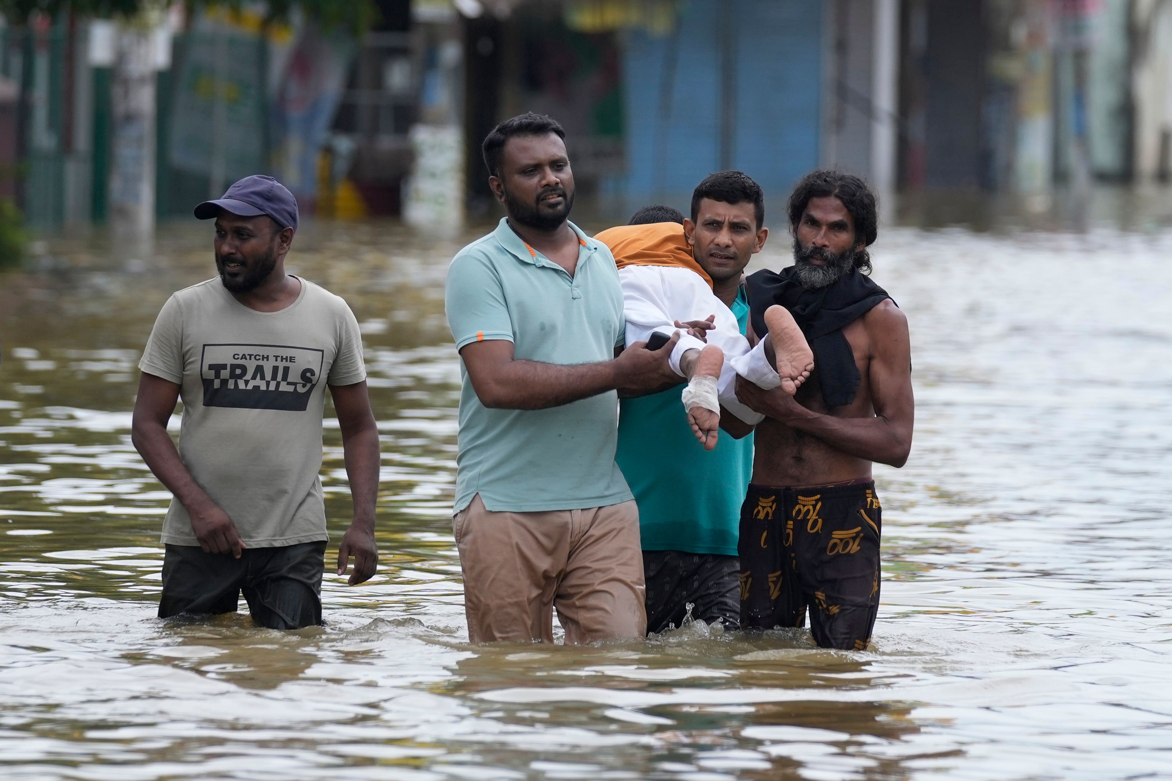 People carry an injured boy as they wade through a flooded street in Biyagama, a suburb of Colombo, Sri Lanka, Monday, Jun. 3, 2023. Sri Lanka closed schools on Monday as heavy rains triggered floods and mudslides in many parts of the island nation, killing at least 10 people while six others have gone missing, officials said.