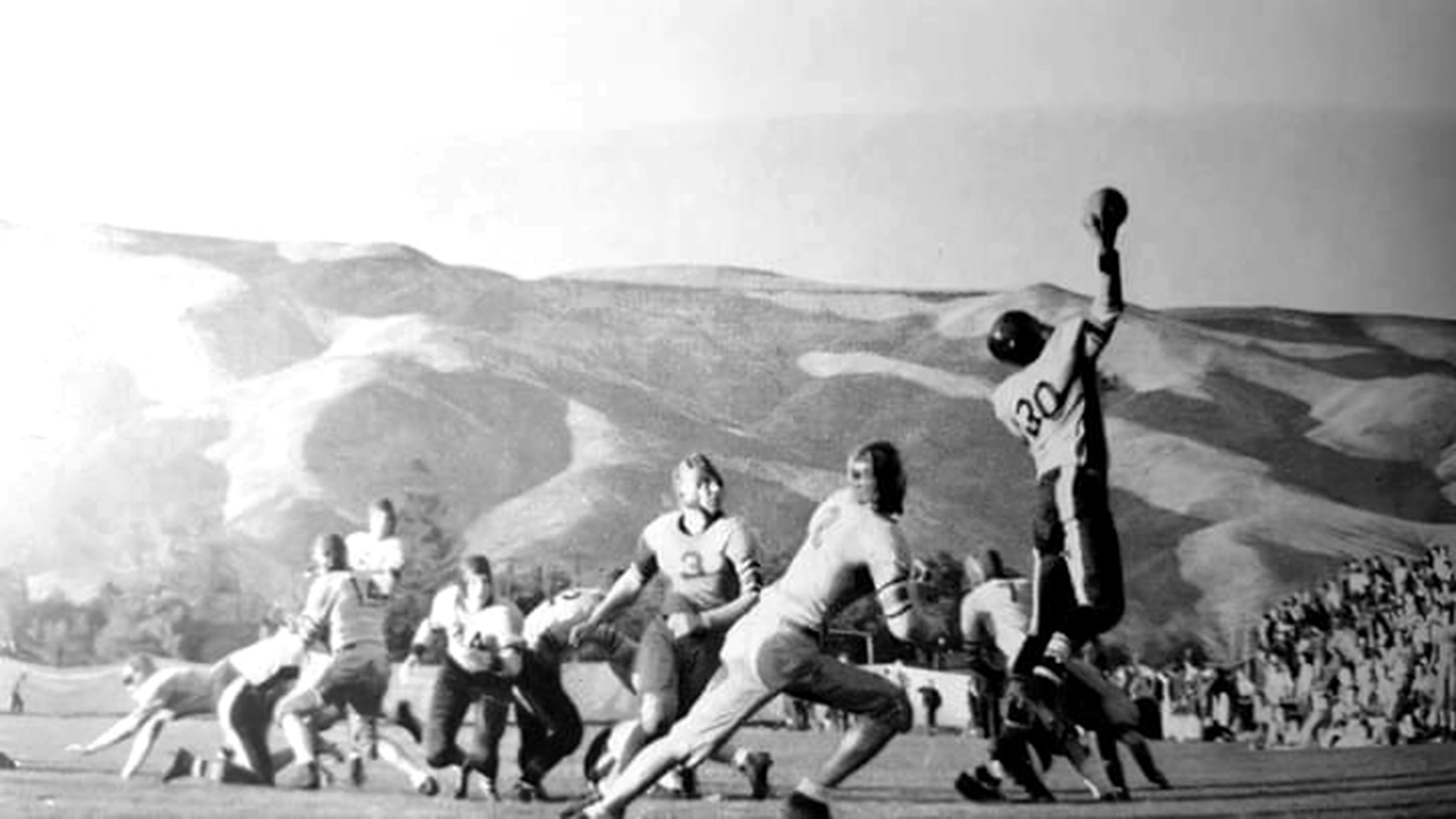 A player leaps for the ball during a football game played in 1936 at Bengal Field.