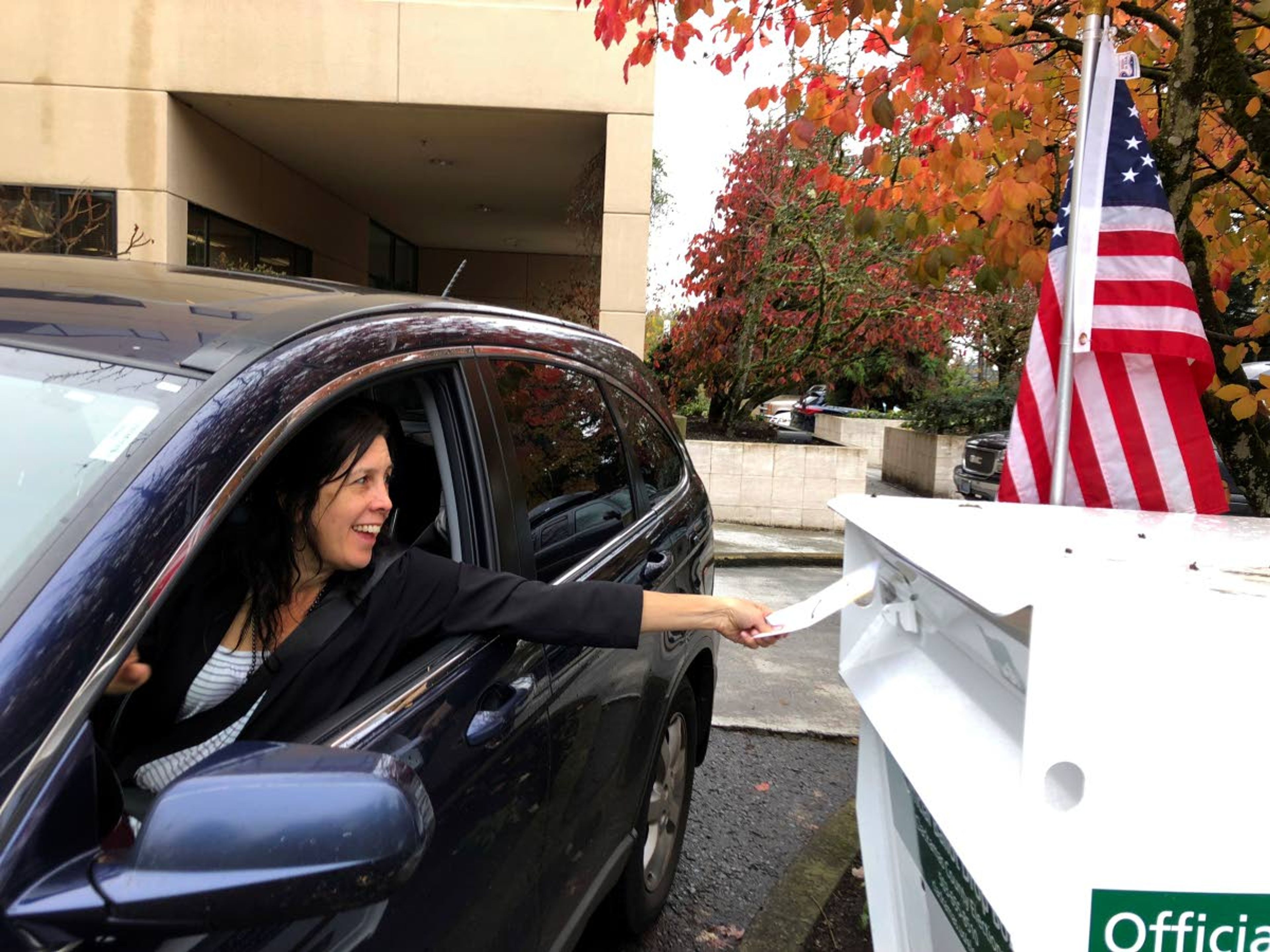 In this Nov. 6, 2018 photo, a voter in Lake Oswego, Ore., places her ballot in a designated drop box outside City Hall.