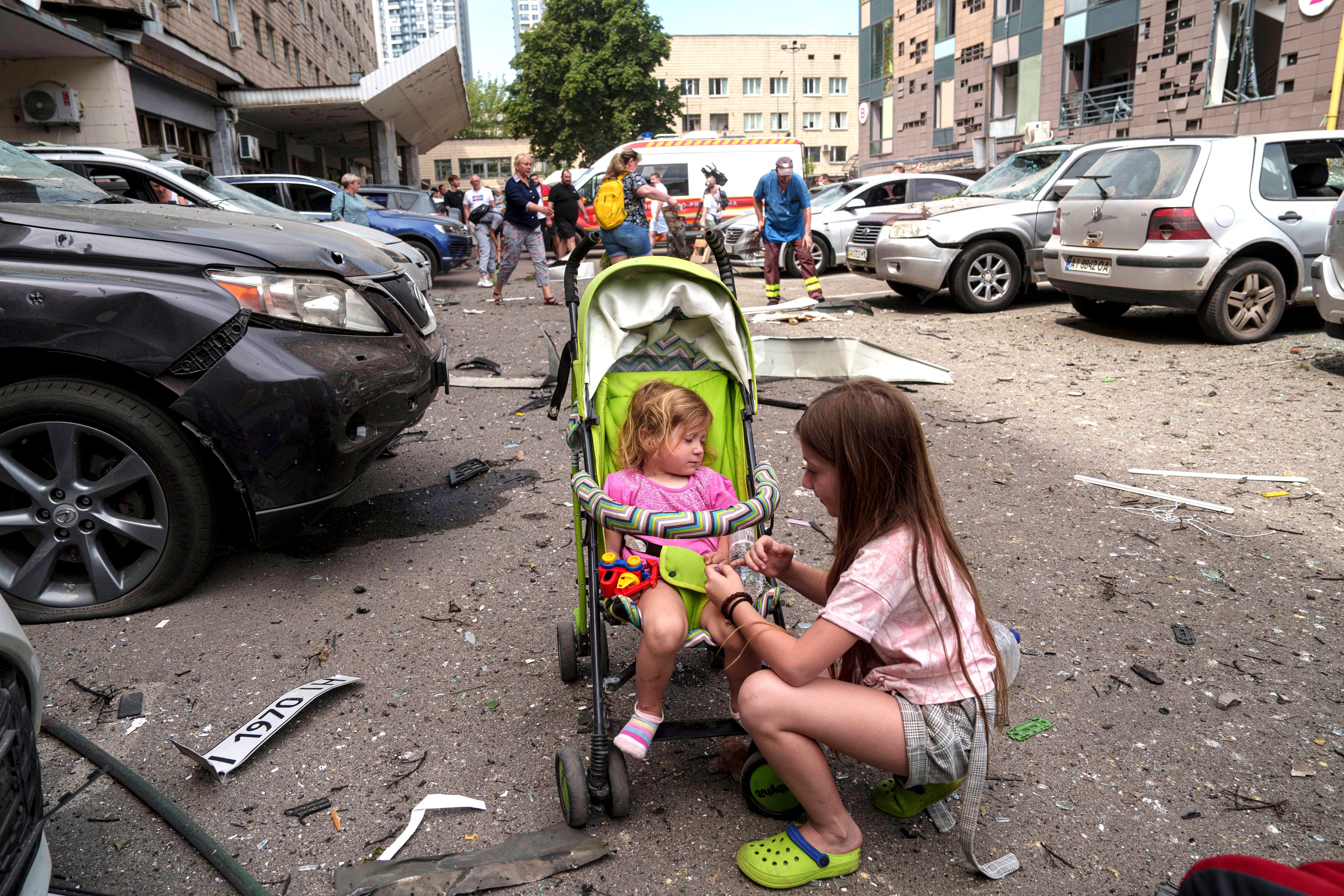 Children wait near the site of Okhmatdyt children’s hospital hit by Russian missiles, in Kyiv, Ukraine, Monday, July 8, 2024. Russian missiles have killed several people and struck a children’s hospital in the Ukrainian capital, Kyiv, authorities say. (AP Photo/Evgeniy Maloletka)