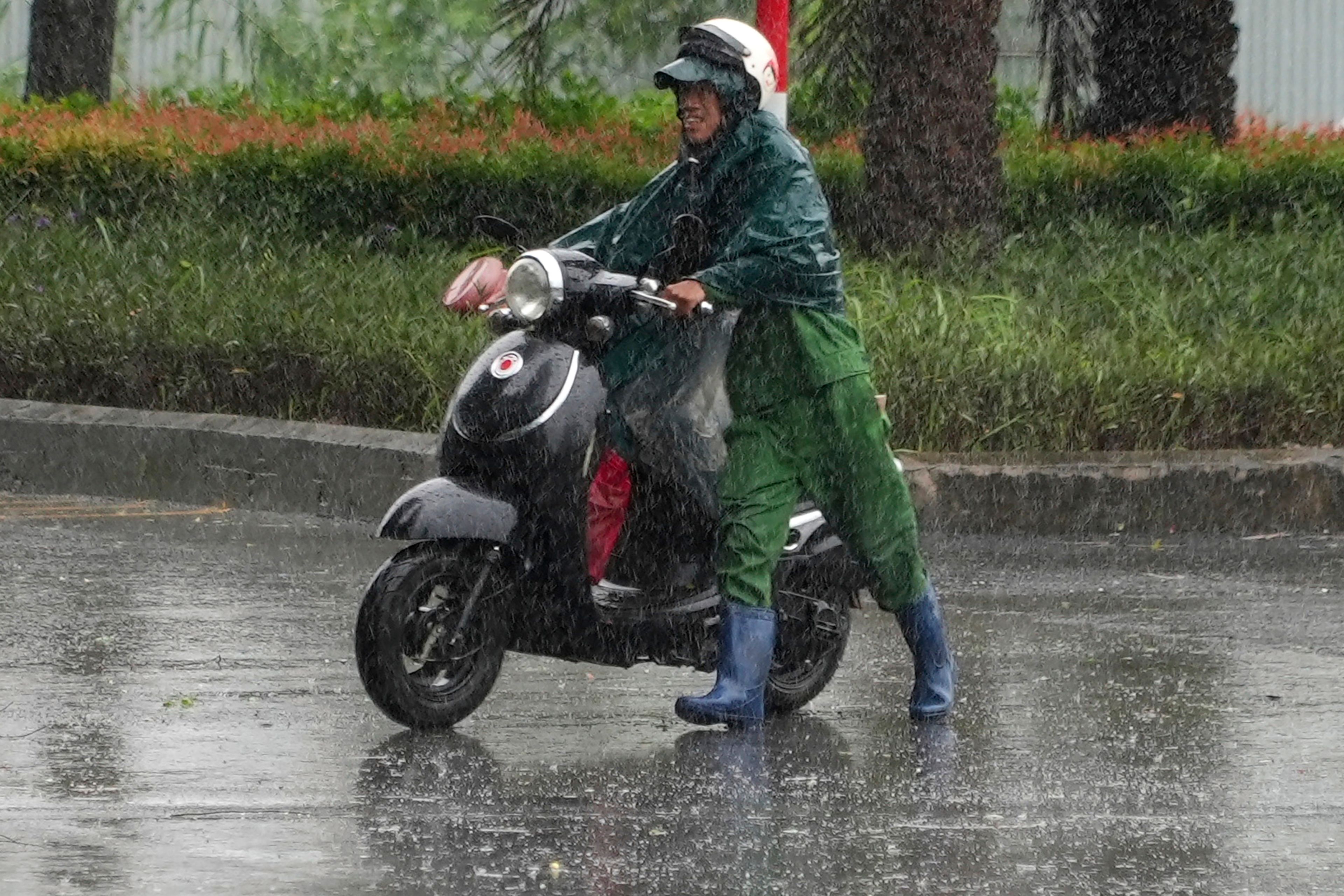 A man pushes a motorcycle in the rain caused by typhoon Yagi in Hanoi, Vietnam Saturday, Sep. 7, 2024.