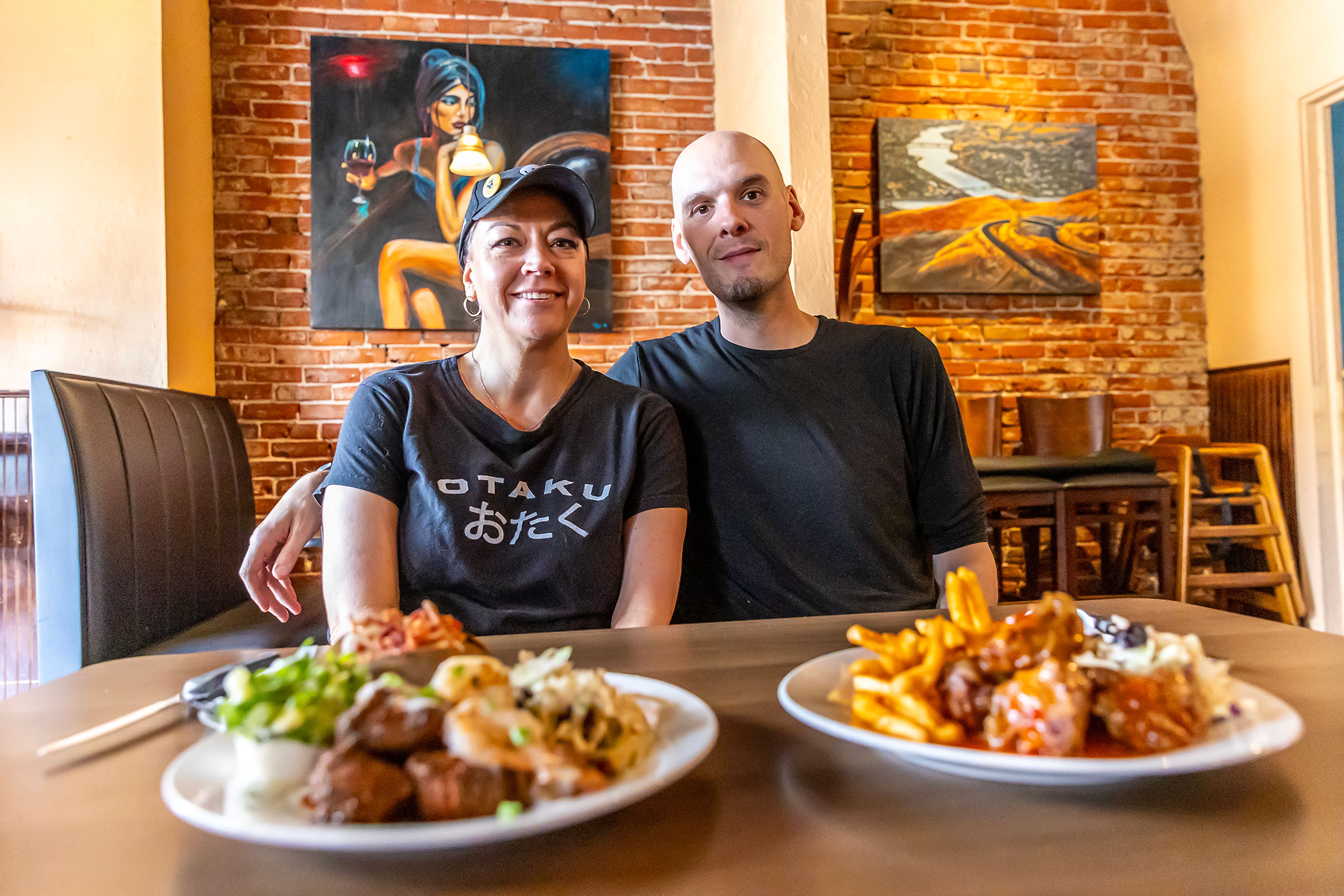 Tina Poe, left, and Ryan M Williams pose for a photo in front of plates of their sweet chili bites and surf and turf at Seasons Bites and Burgers Wednesday in Lewiston.