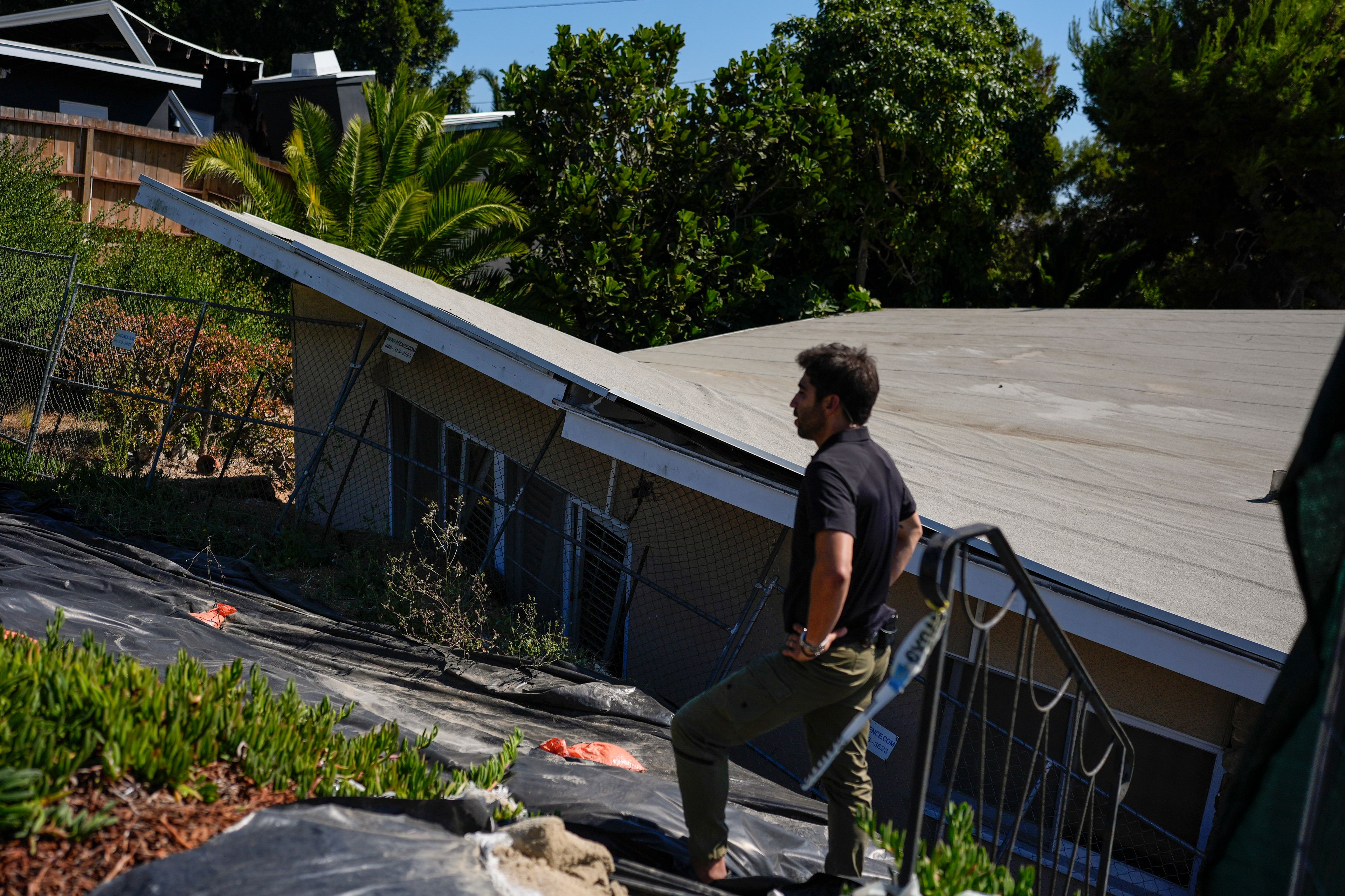 A reporter stands near a home that collapsed due to ongoing landslides in Rancho Palos Verdes, Calif., Tuesday, Sept. 3, 2024.