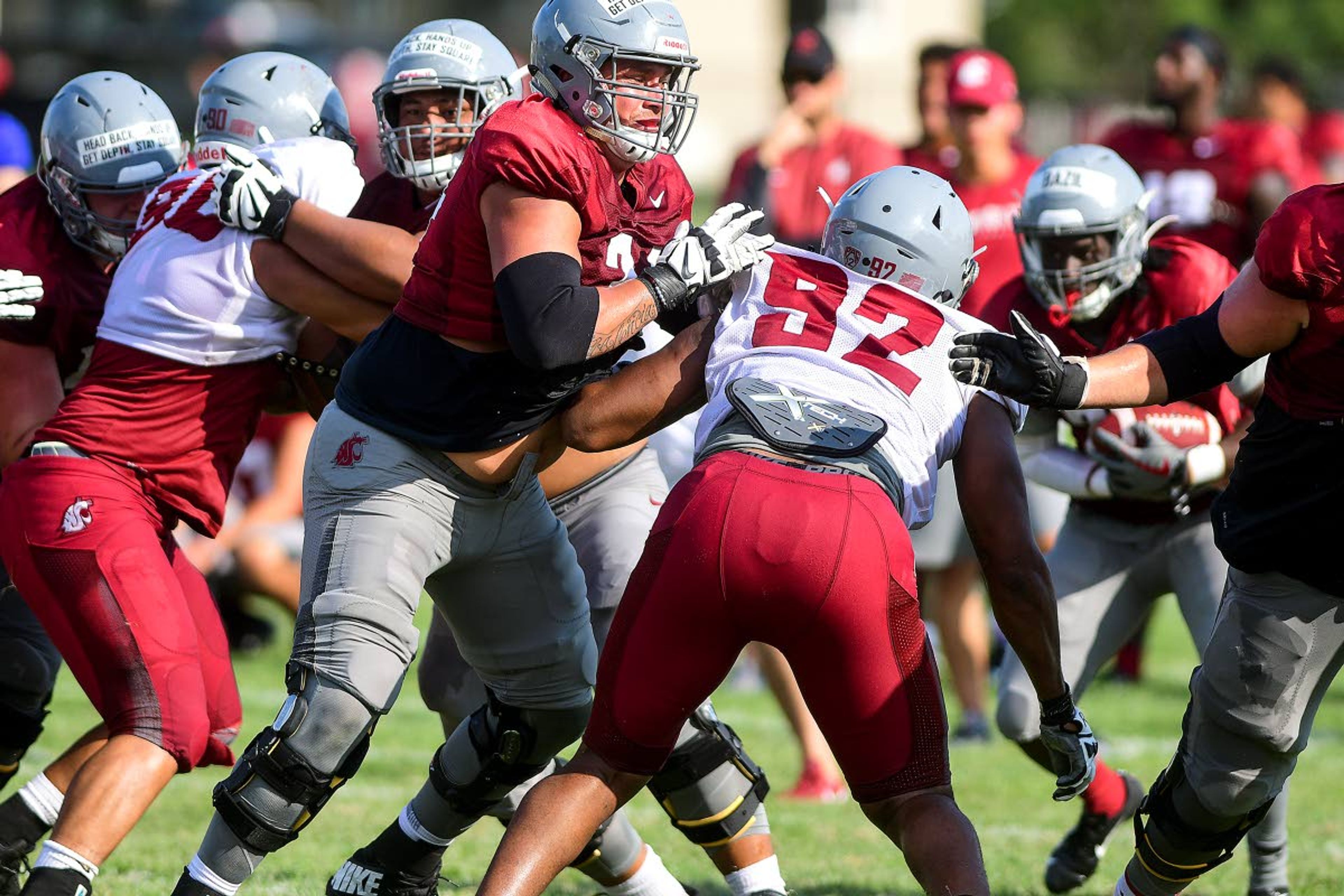 Washington State offensive lineman Robert Valencia blocks defensive lineman Will Rodgers III (92) as ruling back Jouvensly Bazil carries the ball in the back field during team drills on Tuesday in Lewiston.