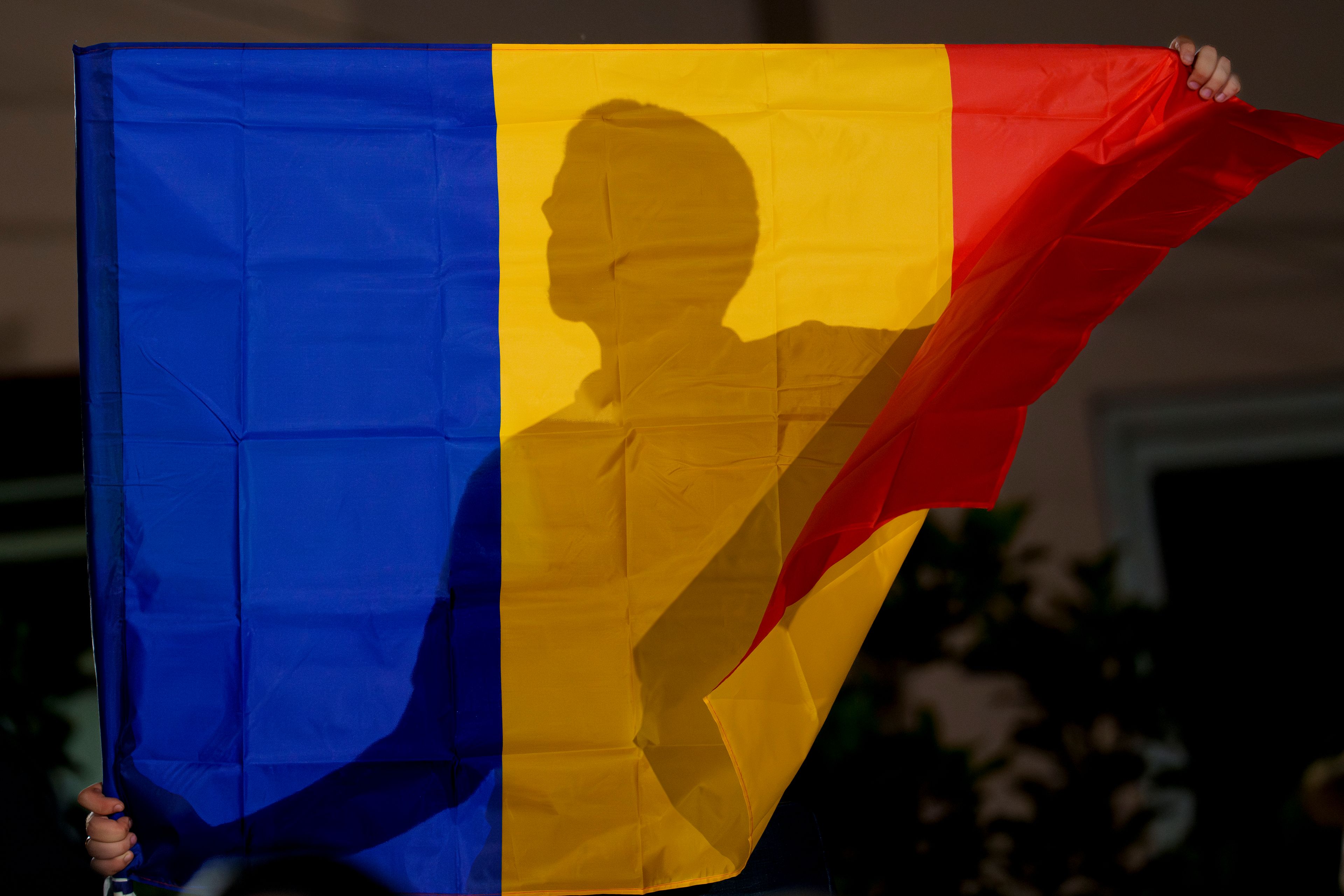 A supporter of the right wing party Alliance for the Unification of Romanians (AUR) holds a flag outside the party headquarters, after the announcement of exit polls in European elections in Bucharest, Romania, Sunday, June 9, 2024.