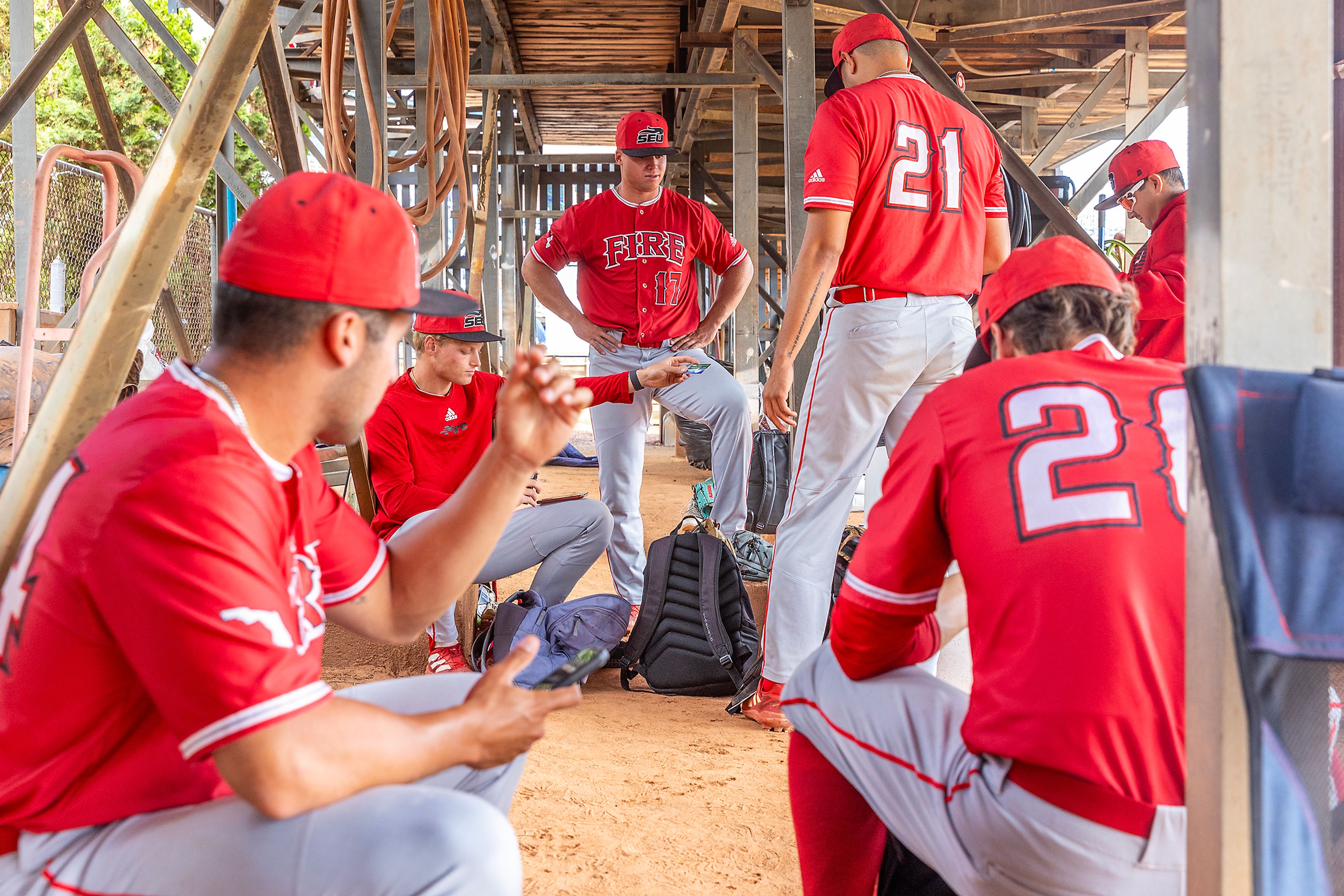 Southeastern players sit under the first base side bleachers during a delay of the game against Tennessee Wesleyan due to lightning in Game 14 of the NAIA World Series on Tuesday at Harris Field in Lewiston.