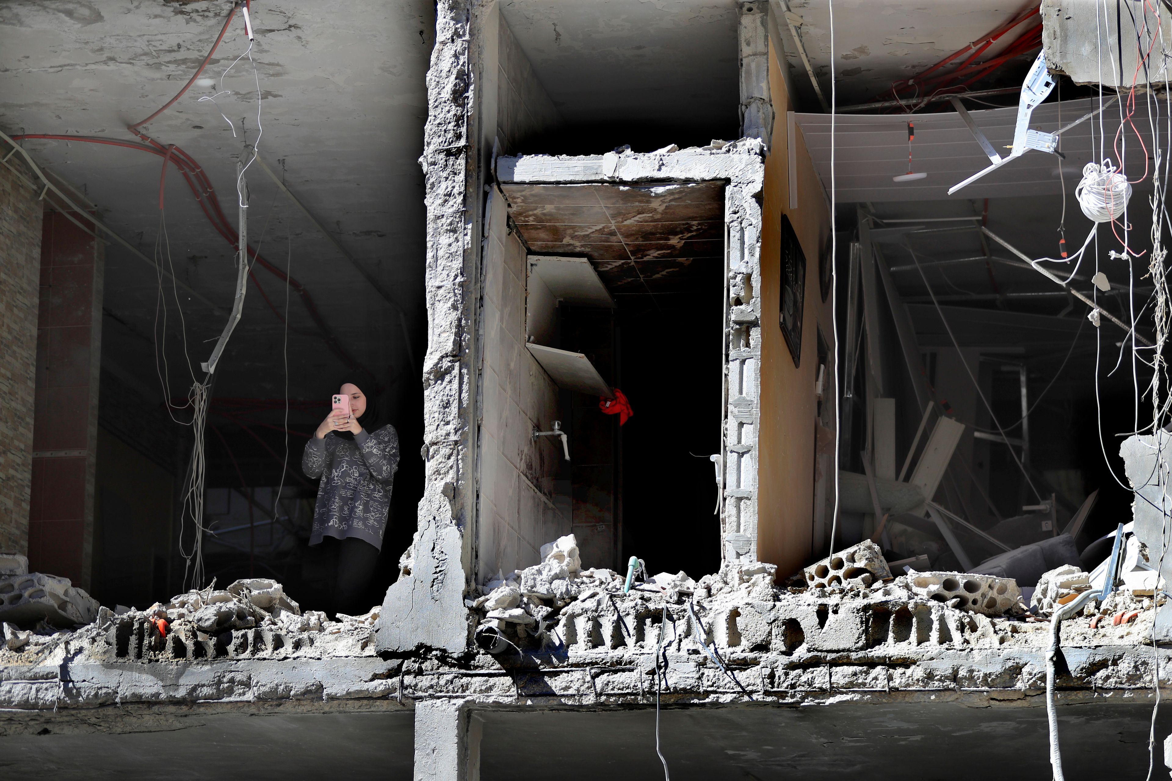 A woman takes pictures by her mobile phone, as she stands at a destroyed apartment that was hit by an Israeli airstrike, in Tyre, south Lebanon, Thursday, Oct. 24, 2024. (AP Photo/Mohammed Zaatari)