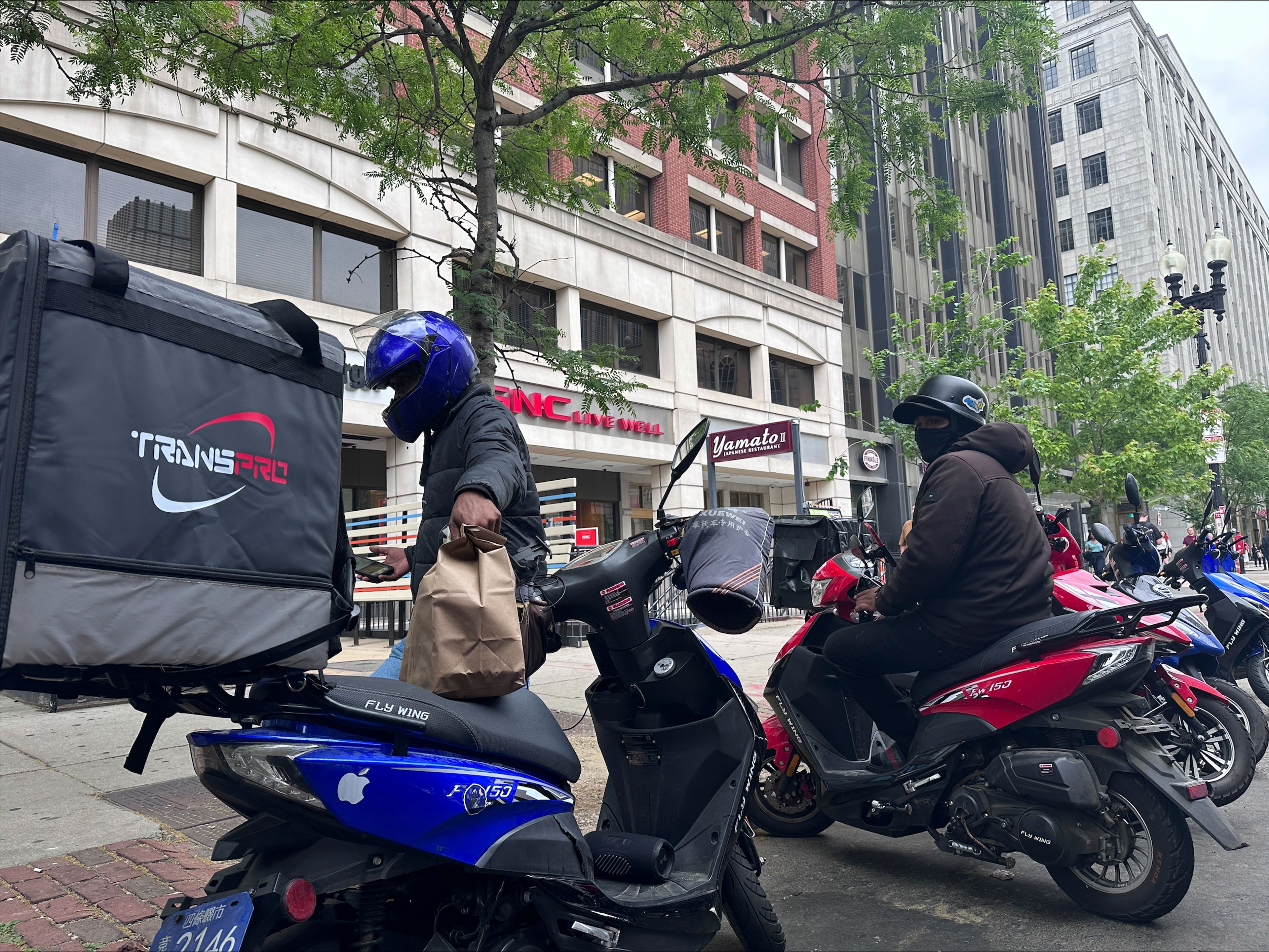 Delivery scooters are parked as drivers wait to pick up food for delivery, Thursday, June 6, 2024, in Boston. Boston and New York are cracking down on unlawful drivers, whom they say are ignoring traffic laws and making city streets more dangerous.