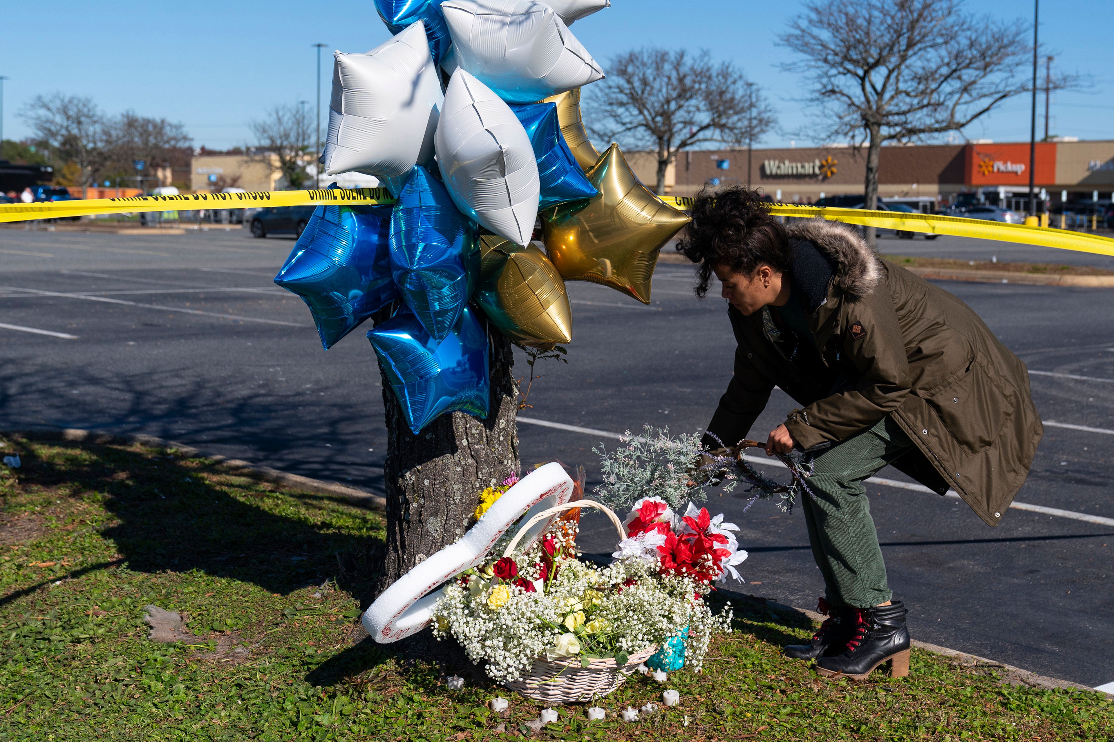 Shyleana Sausedo-Day, from Portsmouth, Va., places flowers near the scene of a mass shooting at a Walmart, Wednesday, Nov. 23, 2022, in Chesapeake, Va. A Walmart manager opened fire on fellow employees in the break room of the Virginia store, killing several people in the countryâ€™s second high-profile mass shooting in four days, police and witnesses said Wednesday. (AP Photo/Alex Brandon)