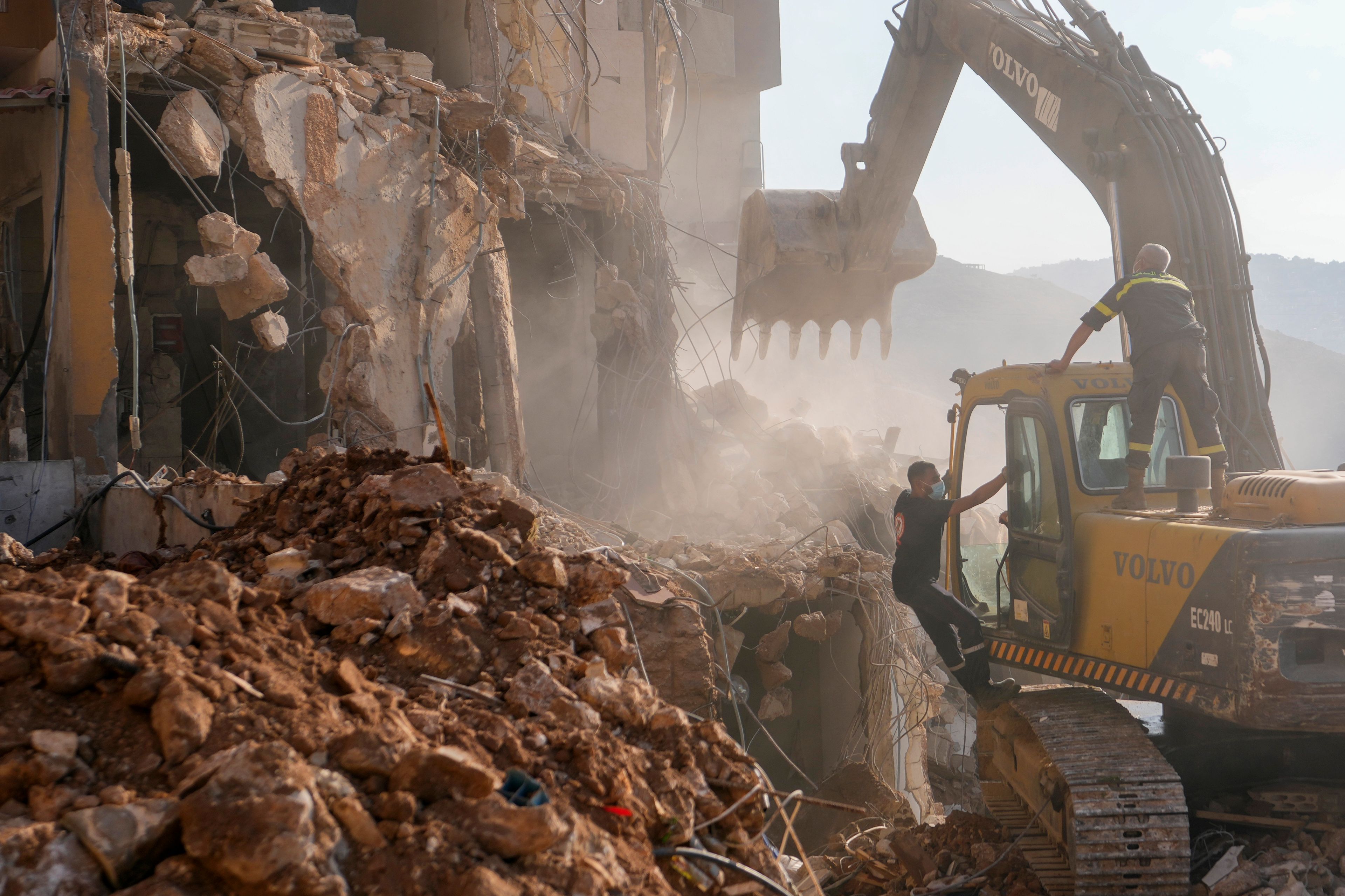 Rescue workers use an excavator to remove the rubble of a destroyed building hit in an Israeli airstrike on Tuesday night, as they search for victims in Barja, Lebanon, Wednesday, Nov. 6, 2024. (AP Photo/Hassan Ammar)