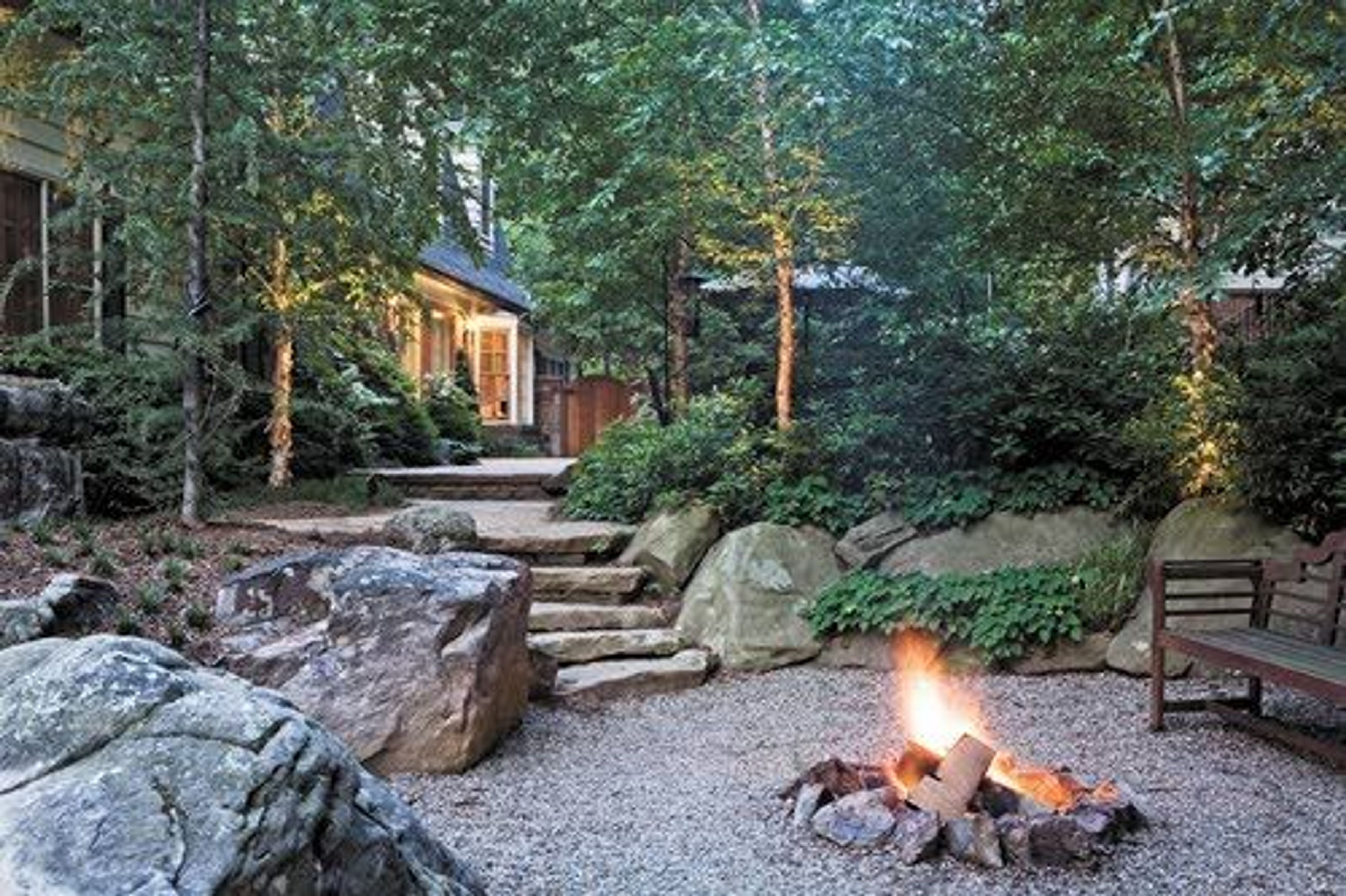 A fire pit evokes a campfire. The boulders and slab steps in this garden make the setting look rustic, but it’s no hike at all from the back door to the warmth of the campfire.