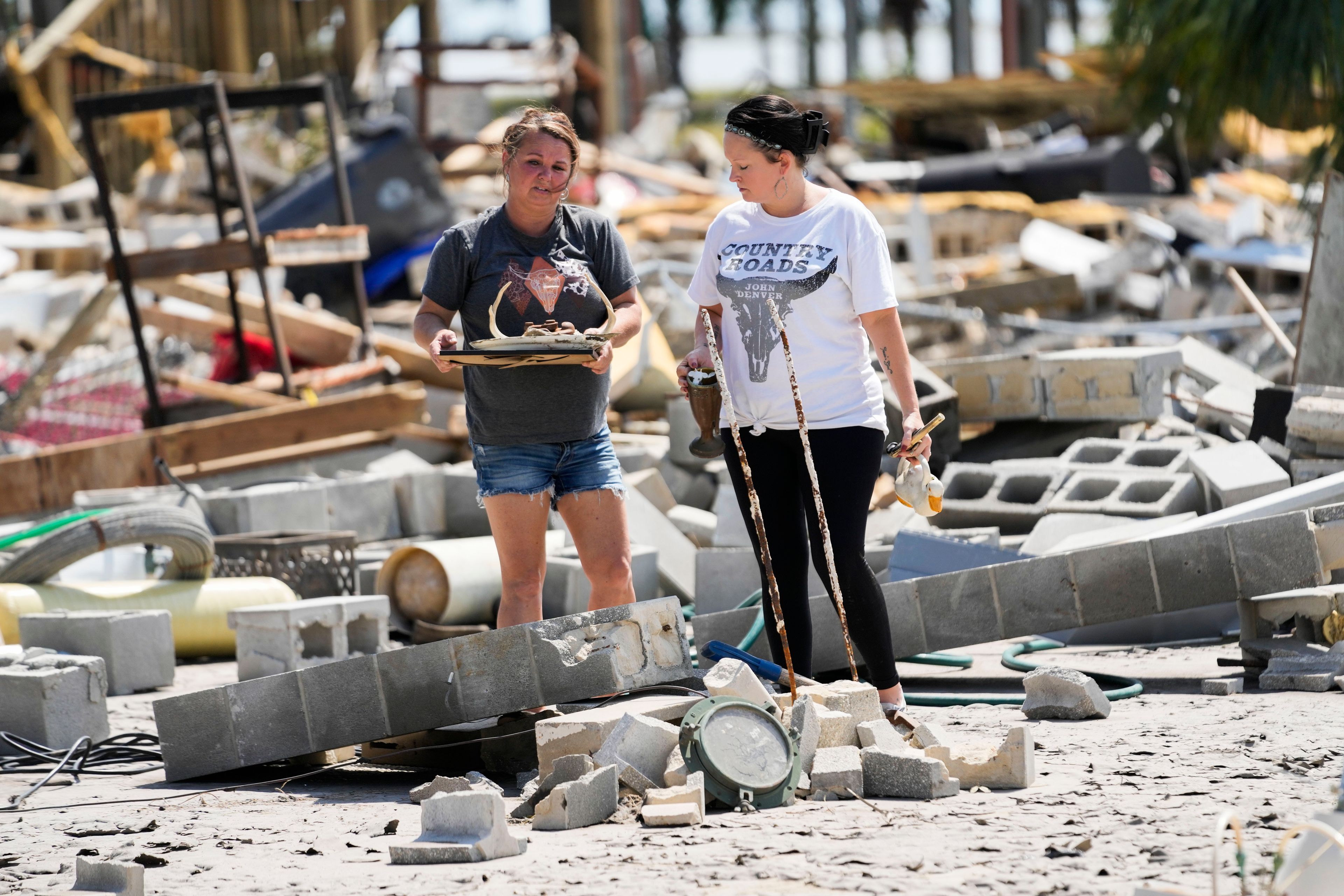 Gloriana Cherry, left, recovers possessions from her family's destroyed home, along with Shannon Lee, in the aftermath of Hurricane Helene, in Horseshoe Beach, Fla., Saturday, Sept. 28, 2024. (AP Photo/Gerald Herbert)