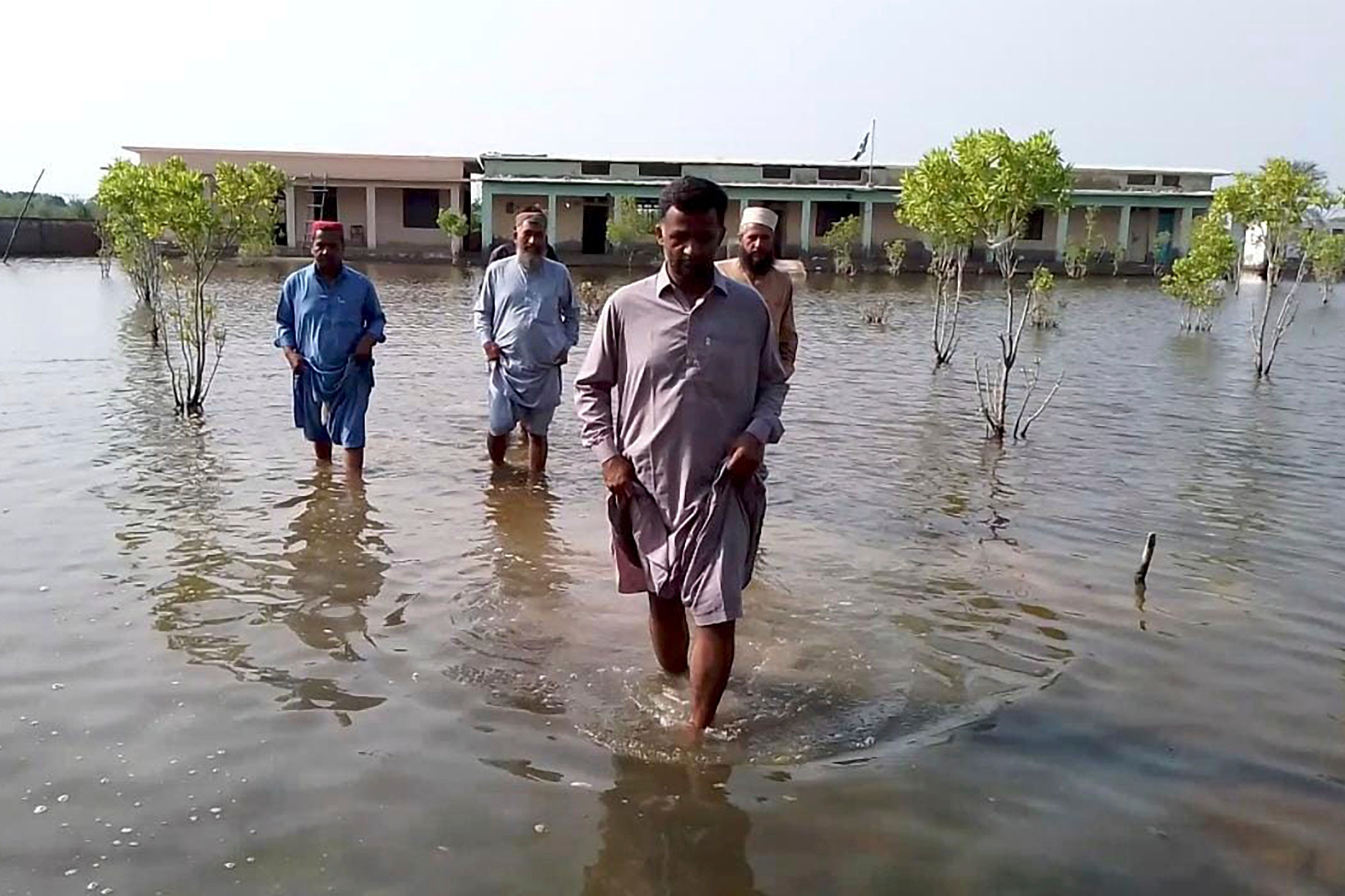 Villagers wade through flood area caused by heavy monsoon rains near Sohbat Pur, an area of Pakistan's southwestern Baluchistan province, Monday, Aug. 19, 2024.