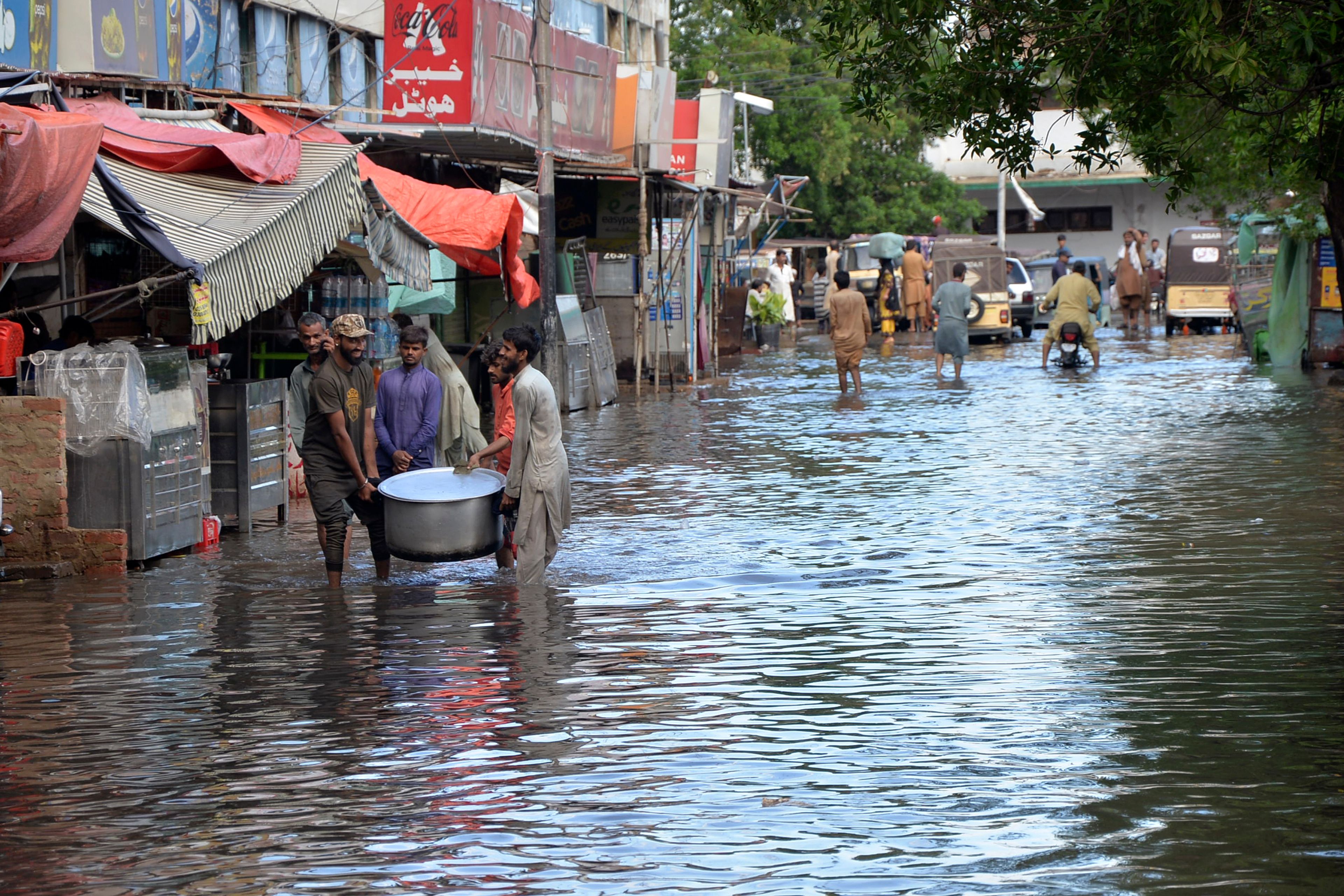 People wade through a flooded road caused by heavy monsoon rain, in Hyderabad, Pakistan, Friday, Aug. 30, 2024.