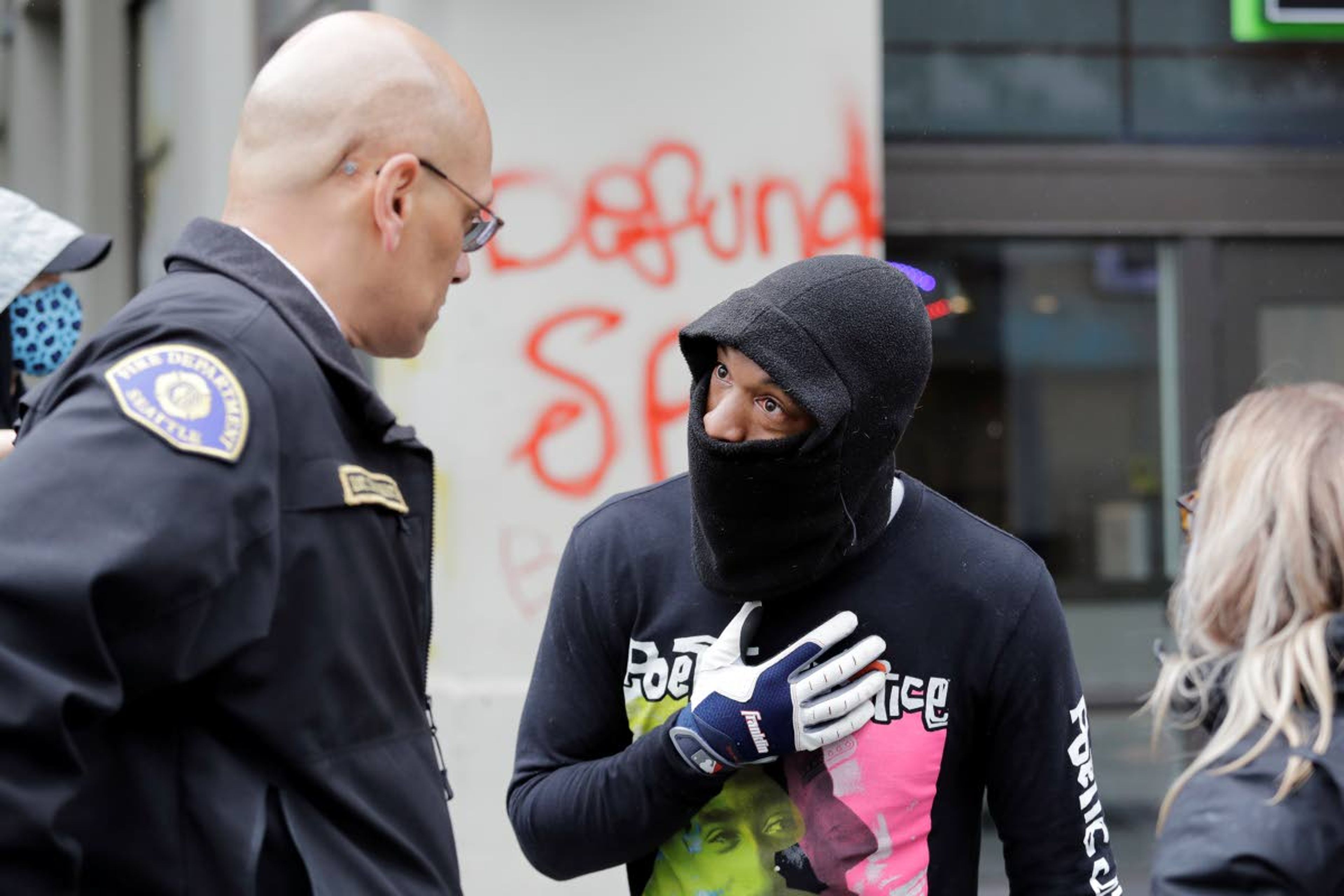 Demonstrator Keith Brown, right, talks with Seattle Fire Dept. Assistant Chief Willie Barrington as they plan to remove makeshift barricades protesters had put up in the streets next to a Seattle police precinct Tuesday, June 9, 2020, in Seattle, following protests over the death of George Floyd. Floyd, a black man died after being restrained by Minneapolis police officers on May 25. (AP Photo/Elaine Thompson)