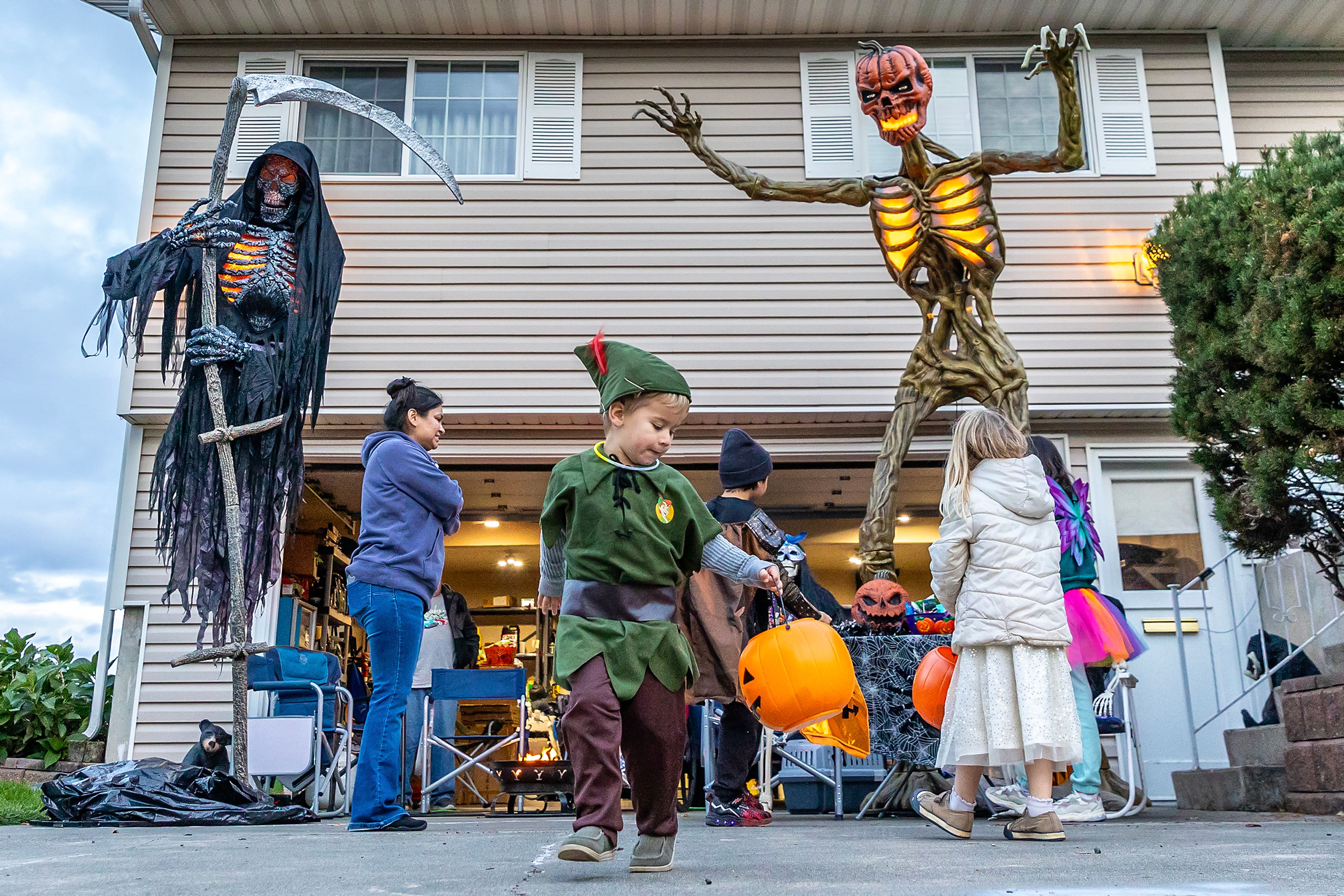 A trick-or-treater dressed as Peter Pan walks back toward the sidewalk after receiving candy Thursday in the Sunset Drive neighborhood in Lewiston.