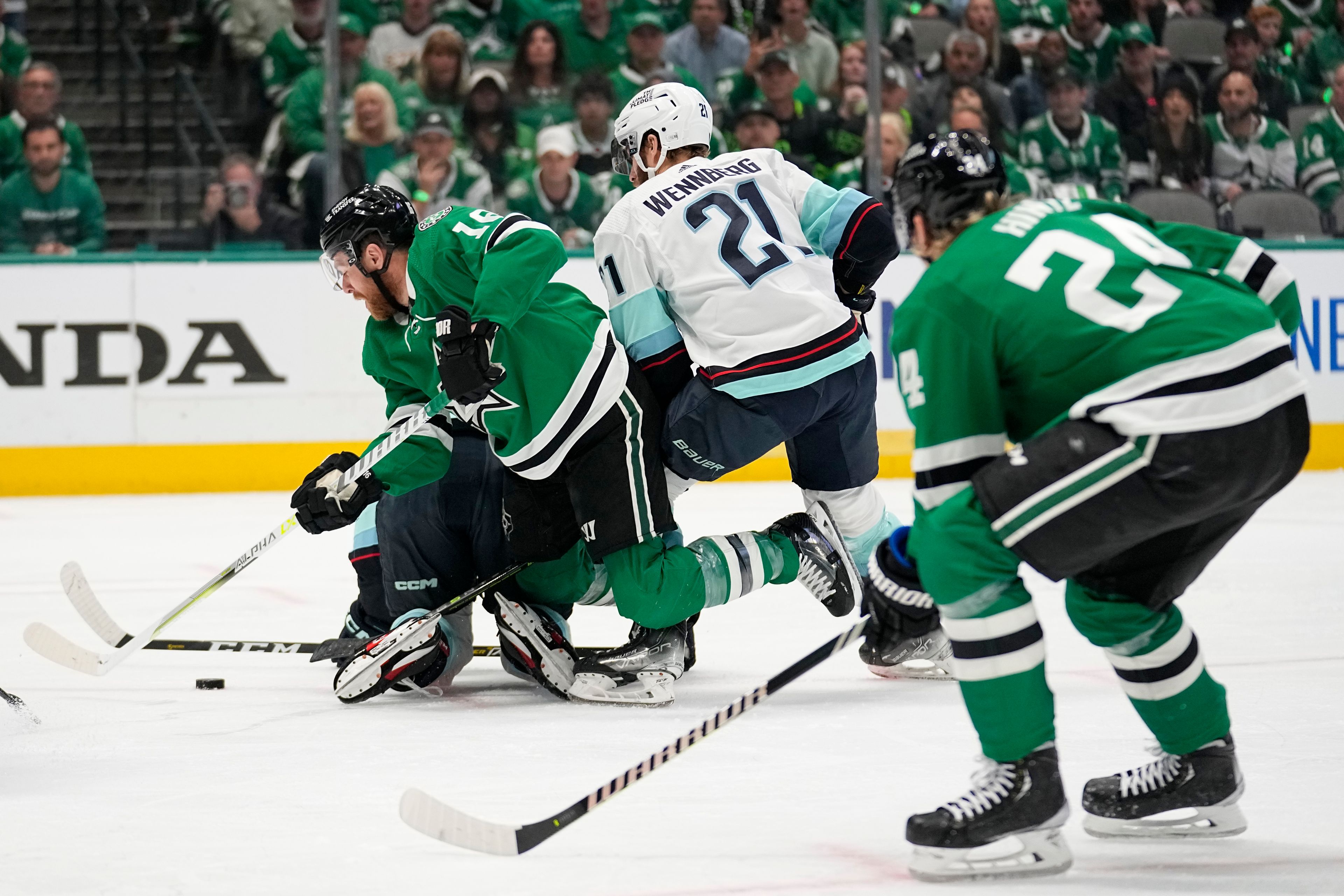 Dallas Stars center Joe Pavelski (16) attempts to take a shot falling to the ice as Seattle Kraken's Alex Wennberg (21) defends in the first period of Game 7 of an NHL hockey Stanley Cup second-round playoff series, Monday, May 15, 2023, in Dallas. Roope Hintz (24) watches the play. (AP Photo/Tony Gutierrez)