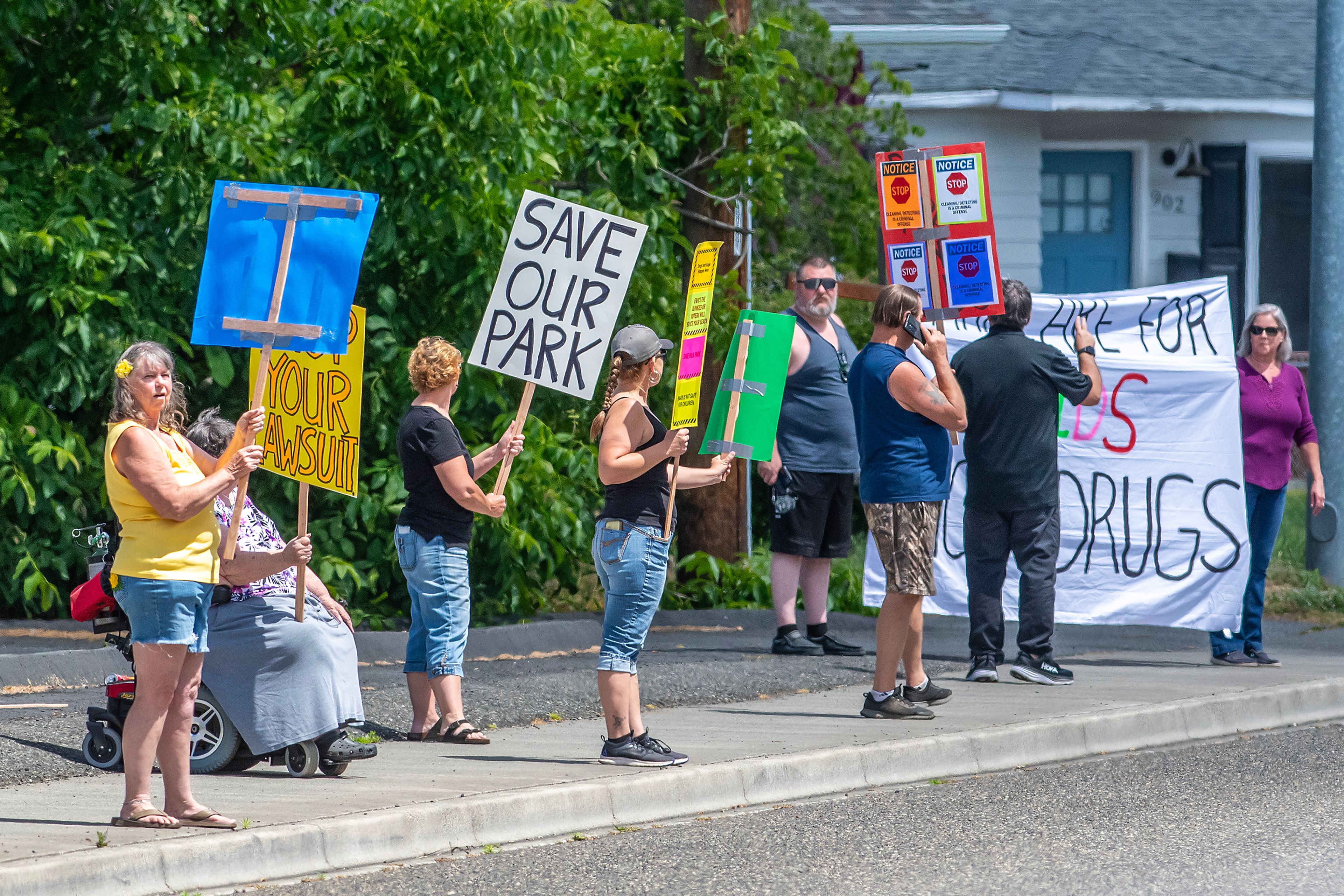 People holds signs as they protest homeless residents at Foster Park Wednesday in Clarkston.