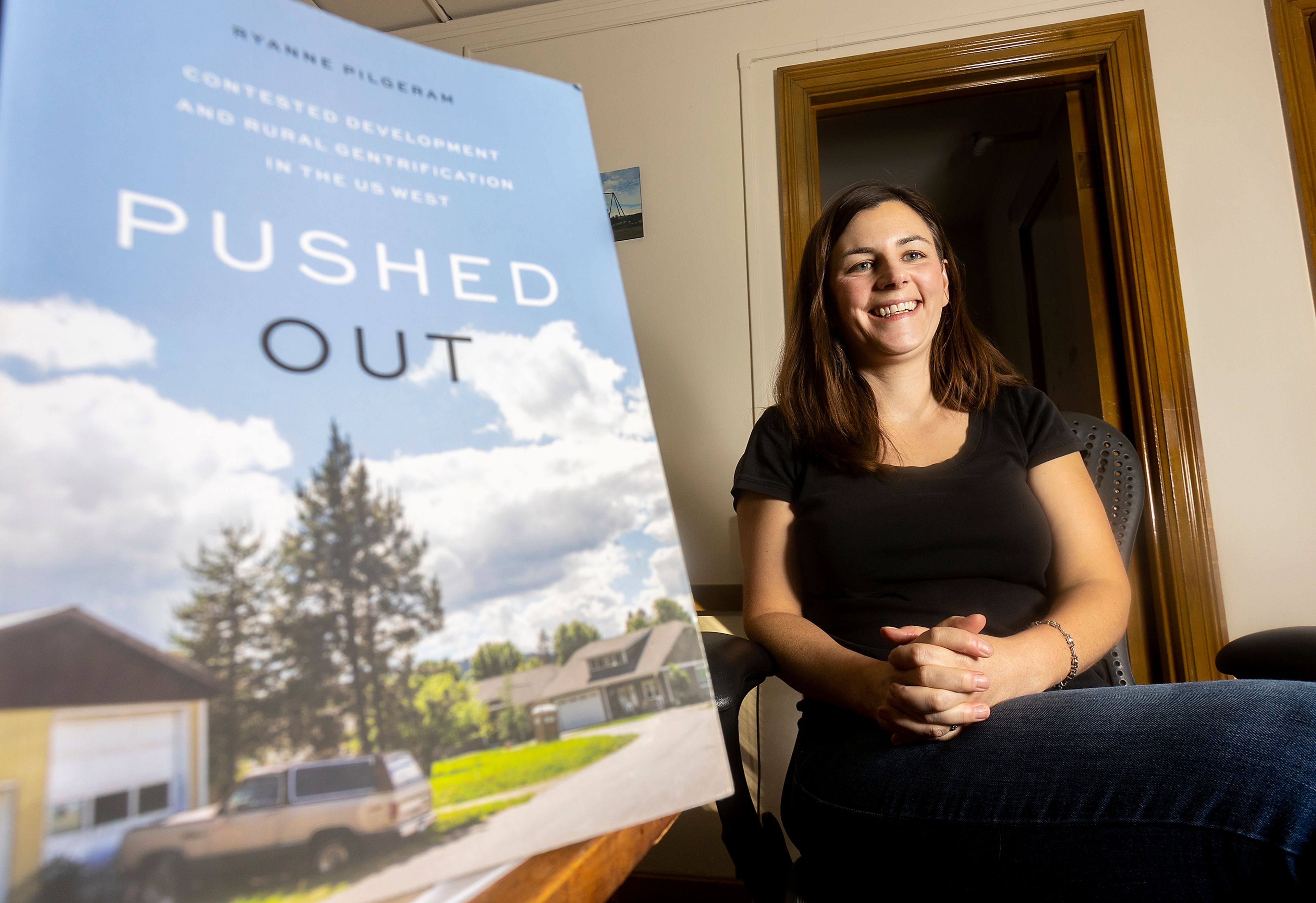 University of Idaho professor Ryan Pilgeram poses for a photo with her book “Pushed Out” in her office in Moscow on Friday.