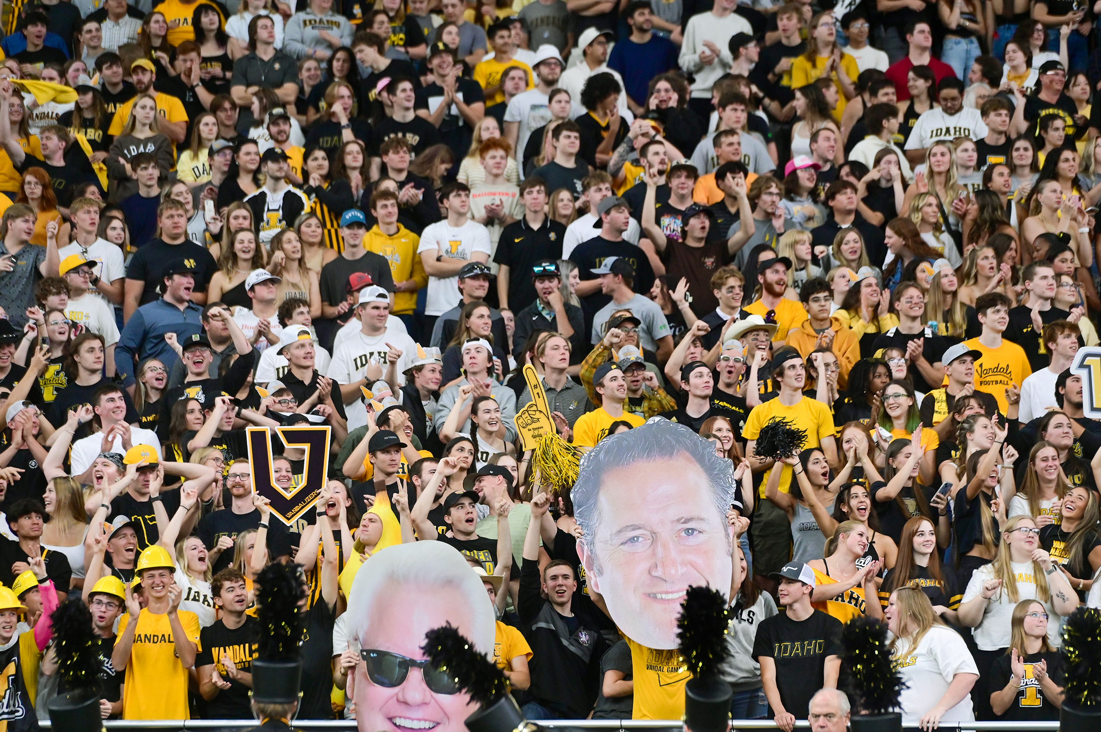 Cutouts of the faces of University of Idaho President C. Scott Green and Idaho head coach Jason Eck are held at the front of a packed student section Saturday at the P1FCU Kibbie Dome in Moscow.,