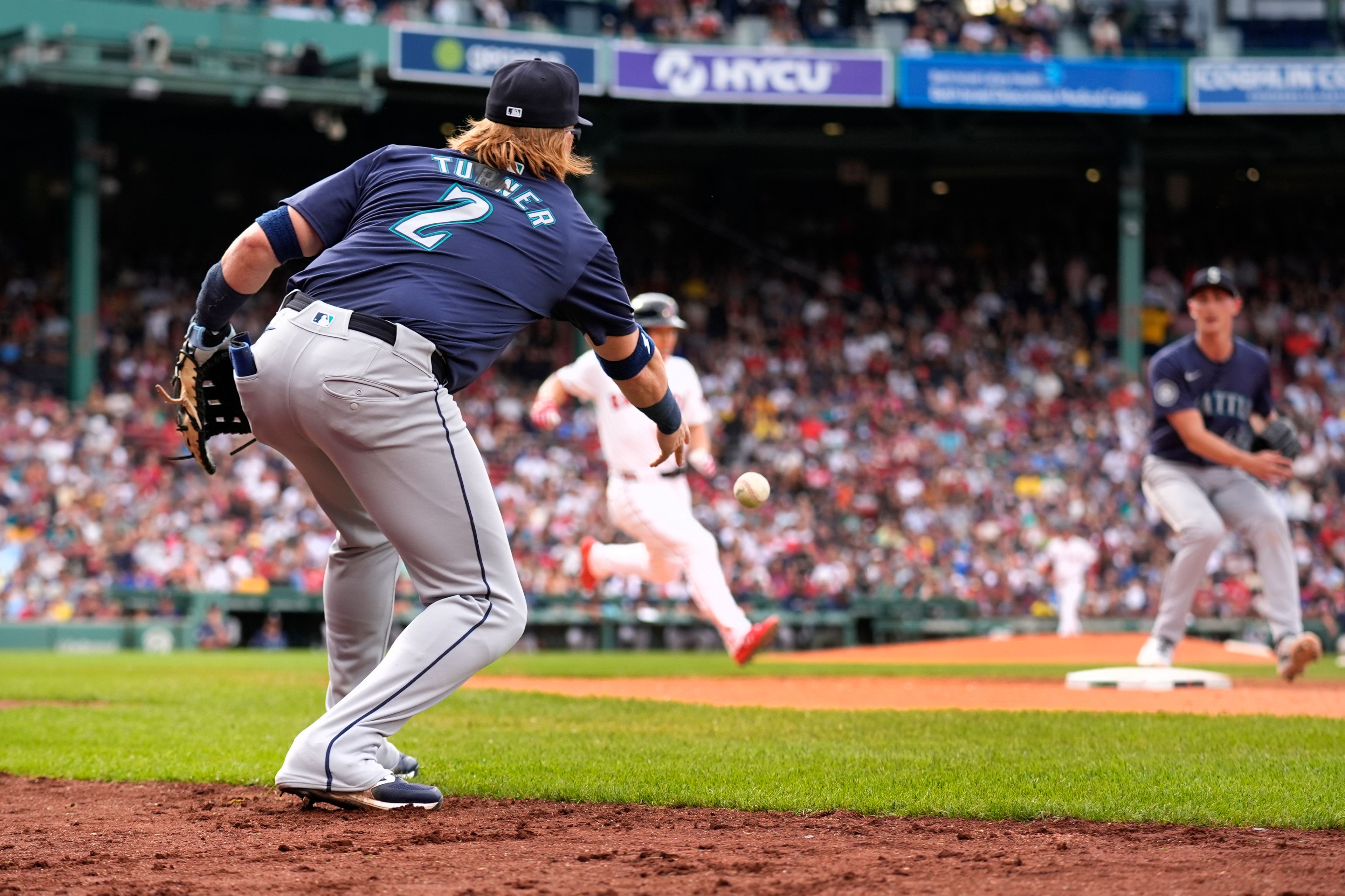 Seattle Mariners first baseman Justin Turner (2) tries to throw out Boston Red Sox's Masataka Yoshida, center, as pitcher George Kirby, right, covers first after a fielding error by Turner during the third inning of a baseball game, Wednesday, July 31, 2024, in Boston. (AP Photo/Charles Krupa)