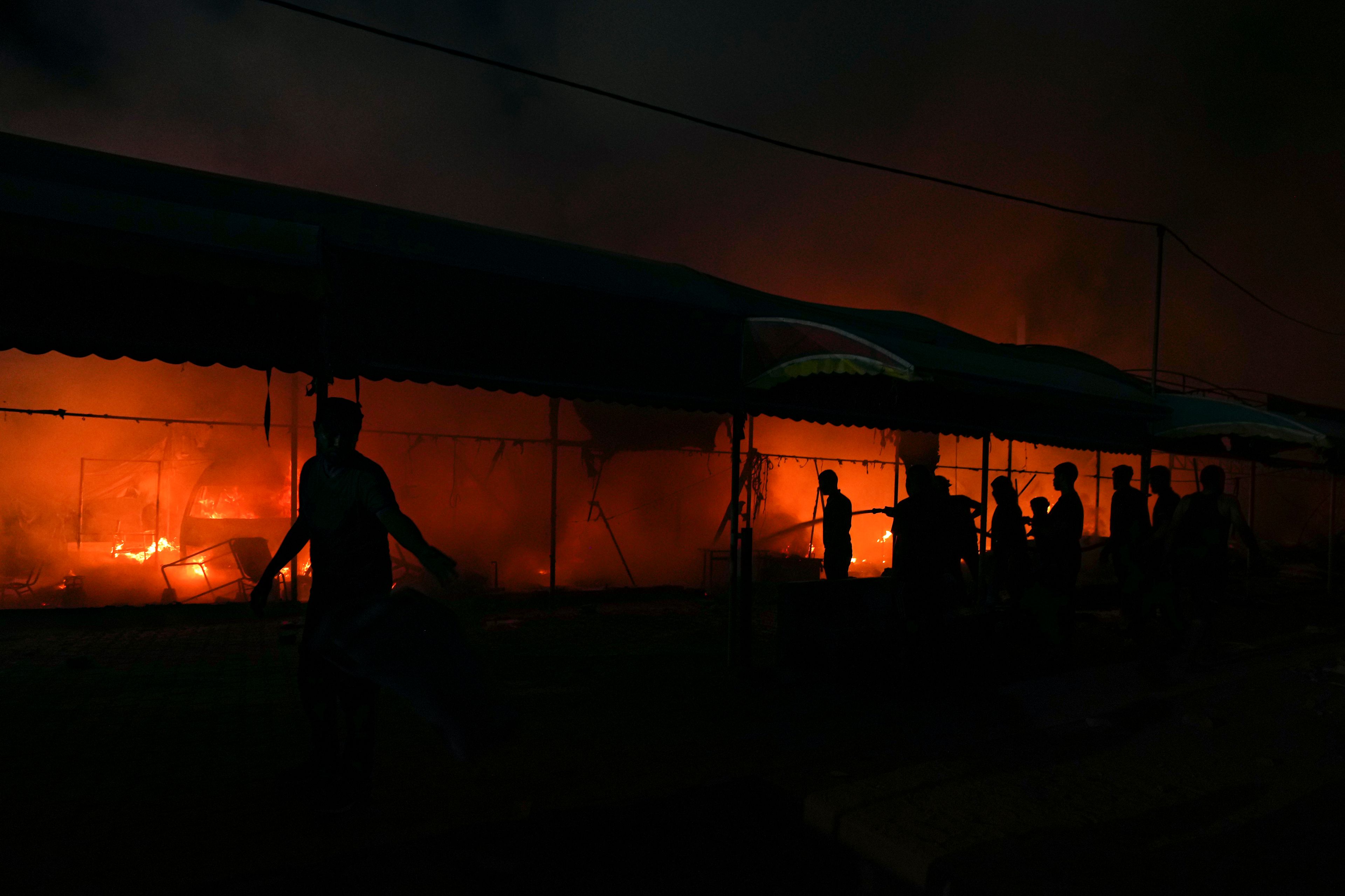 Palestinians try to extinguish a fire caused by an Israeli strike that hit a tent area in the courtyard of Al Aqsa Martyrs hospital in Deir al Balah, Gaza Strip, Monday, Oct. 14, 2024. (AP Photo/Abdel Kareem Hana)