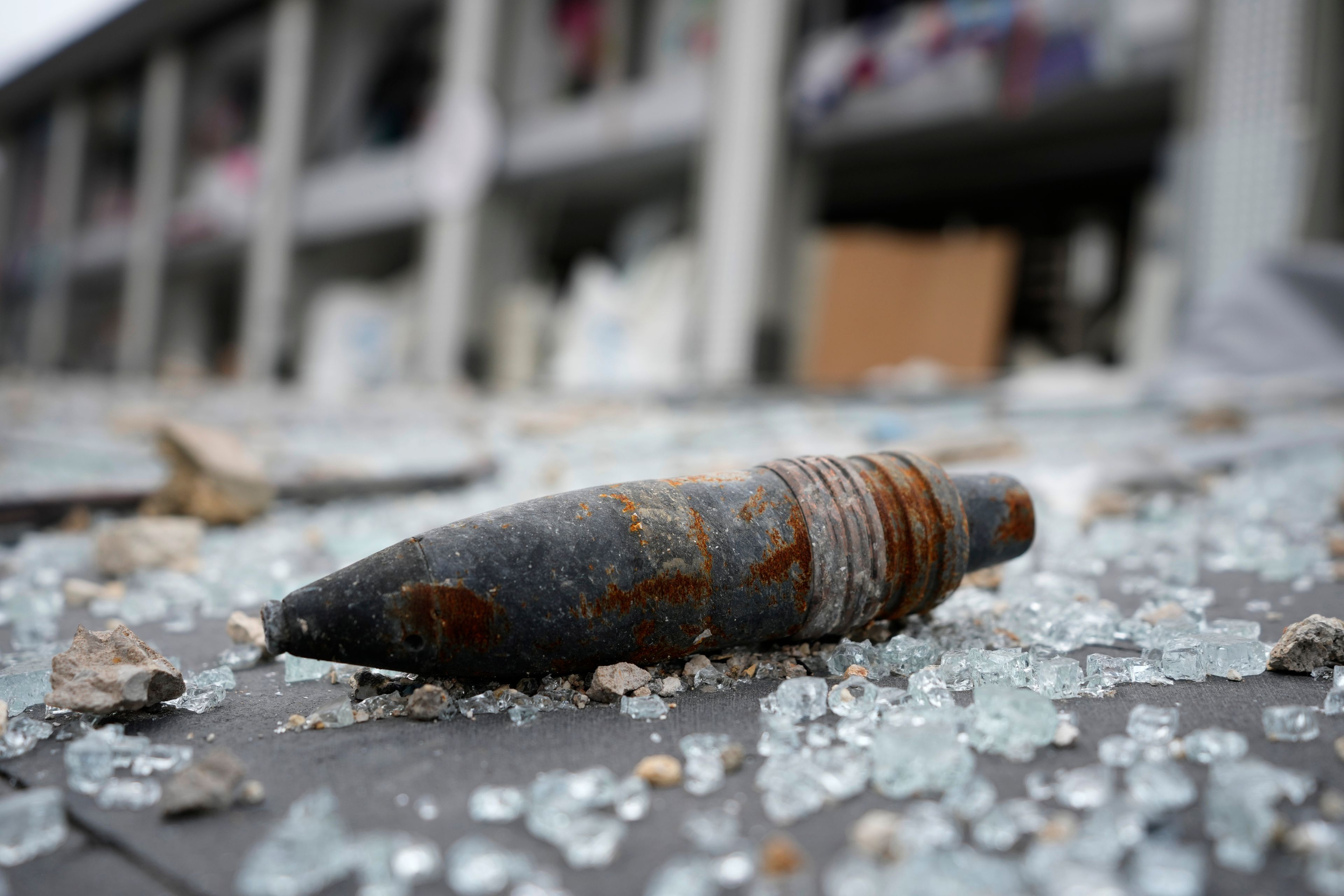 A part of an unexploded bomb lies on the street in front of a destroyed shopping center, following a ceasefire between Israel and Hezbollah that went into effect on Wednesday, Nov. 27, 2024, in Tyre, southern Lebanon. (AP Photo/Hussein Malla)