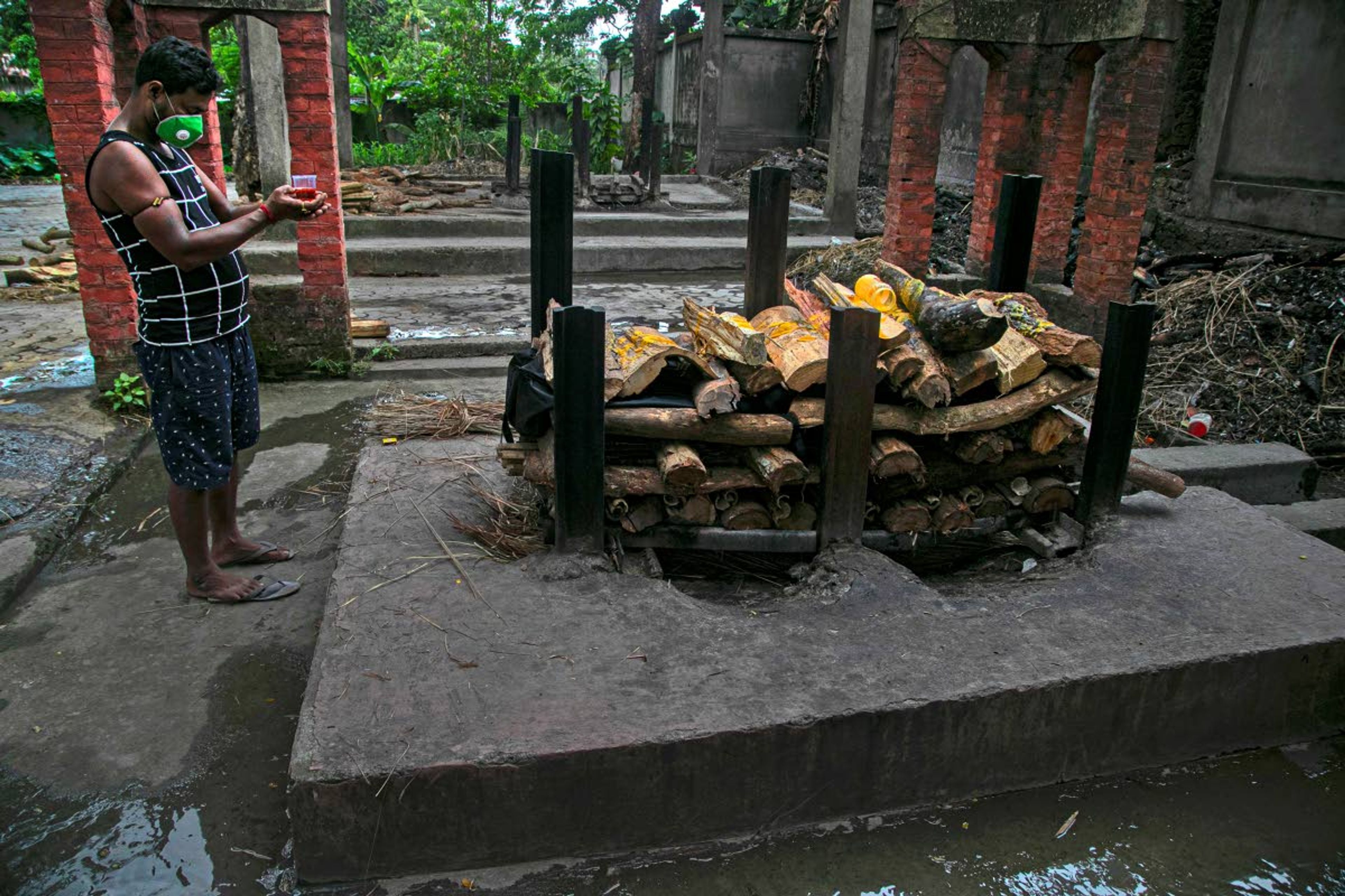 Ramananda Sarkar, 43, offers alcohol to Goddess Kali before cremating a body of a COVID-19 victim in Gauhati, India, Tuesday, Sept. 15, 2020. Sarkar, who was deep in debt and desperate for money, took the job of lighting funeral pyres after failing to pay back a loan he'd taken to start selling sugarcane juice on a wooden cart. With a mask on his face and a prayer on his lips, he cremates bodies brought in by a handful of relatives in protective suits, hurried affairs conducted with minimal rituals under the state government’s guidelines. Sarkar said he alone has cremated more than 450 COVID-19 victims. (AP Photo/Anupam Nath)