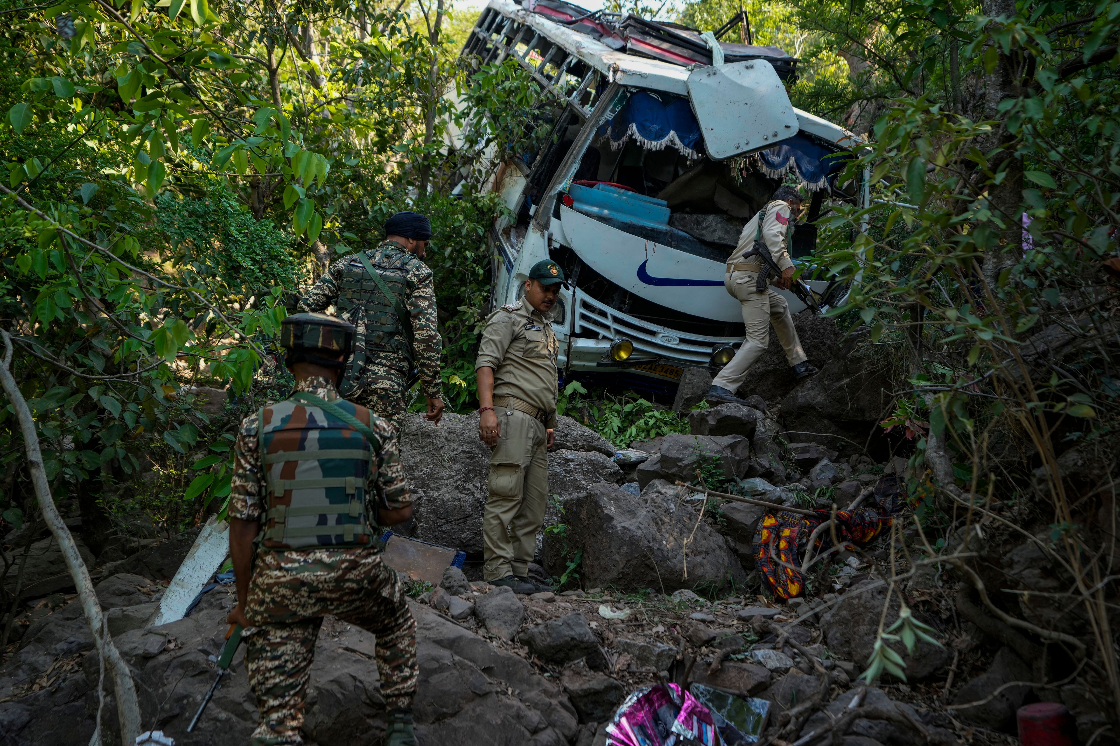 Security men inspect a bus that fell into a deep gorge on Sunday after it was fired at by suspected militants in Reasi district, Jammu and Kashmir, Monday, June 10, 2024. The bus was carrying pilgrims to the base camp of the famed Hindu temple Mata Vaishno Devi when it came under attack killing at least nine people.