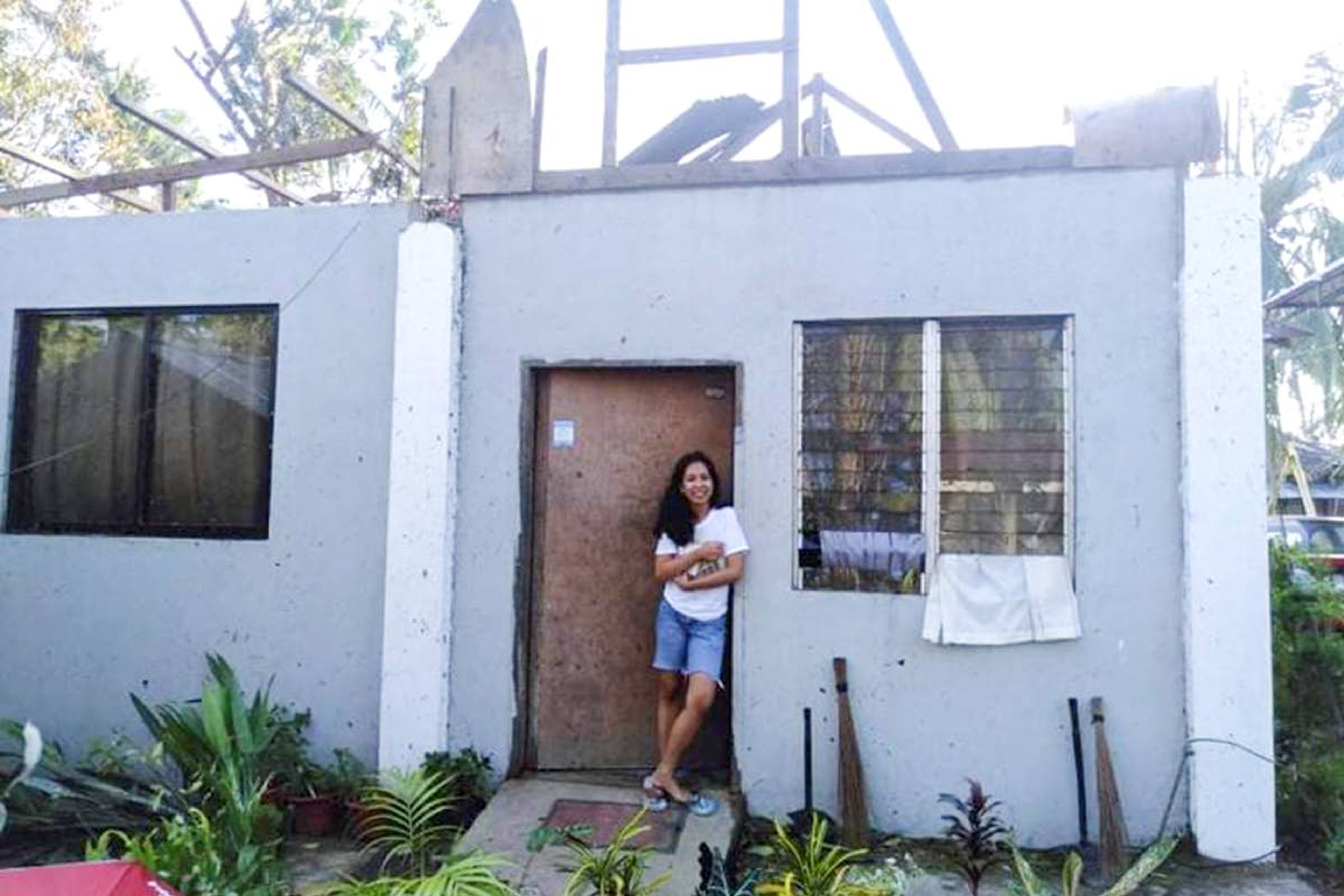 Chyze Montuya Adkison stands outside her home in the Philippines after a storm passed over her family for eight hours.