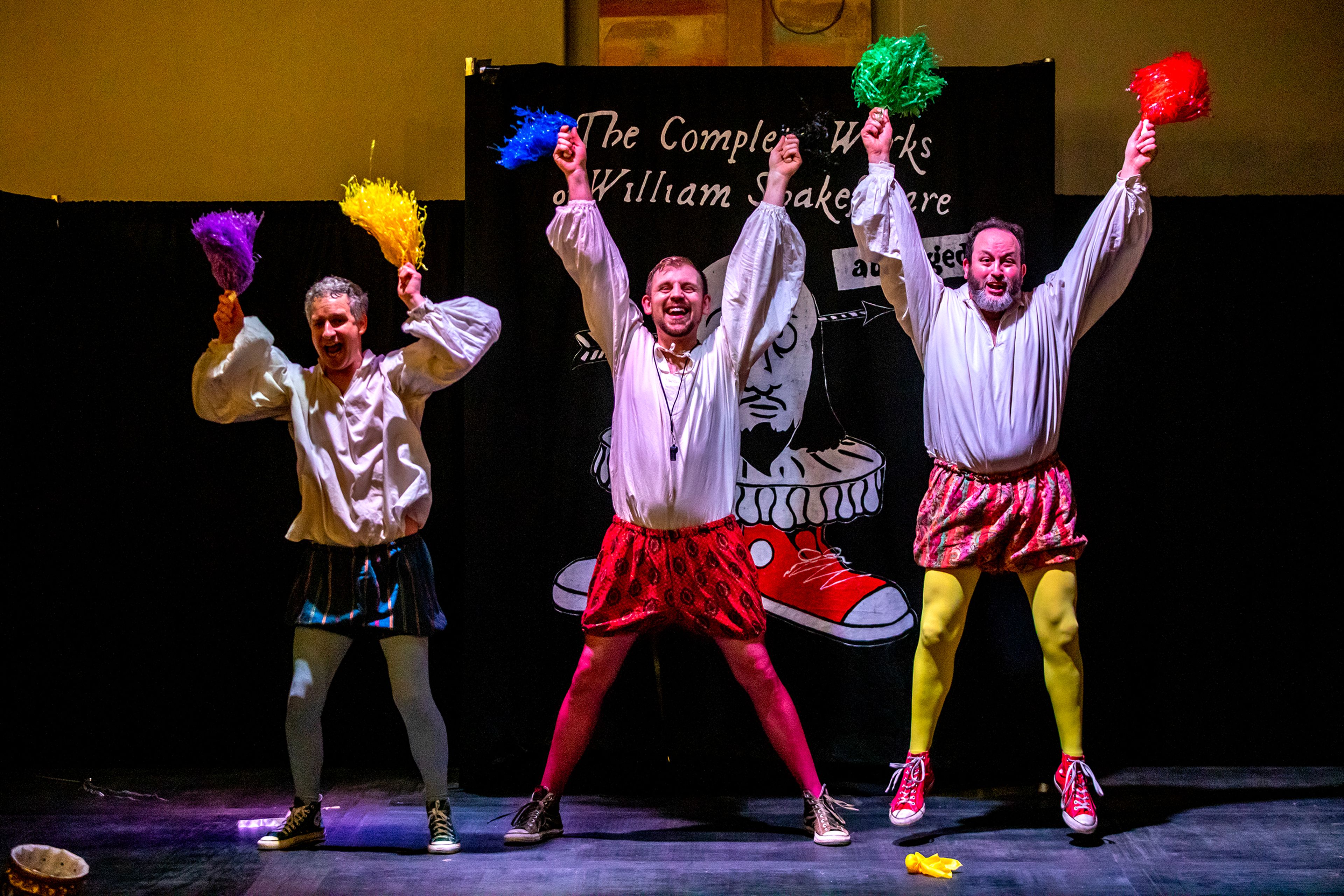 From left: Travis Osburn, Micheal Keene and Jacob Trickey throw their pompoms into the air during a rehearsal for “The Complete Works of William Shakespeare (Abridged).” The show has been extended through this weekend.