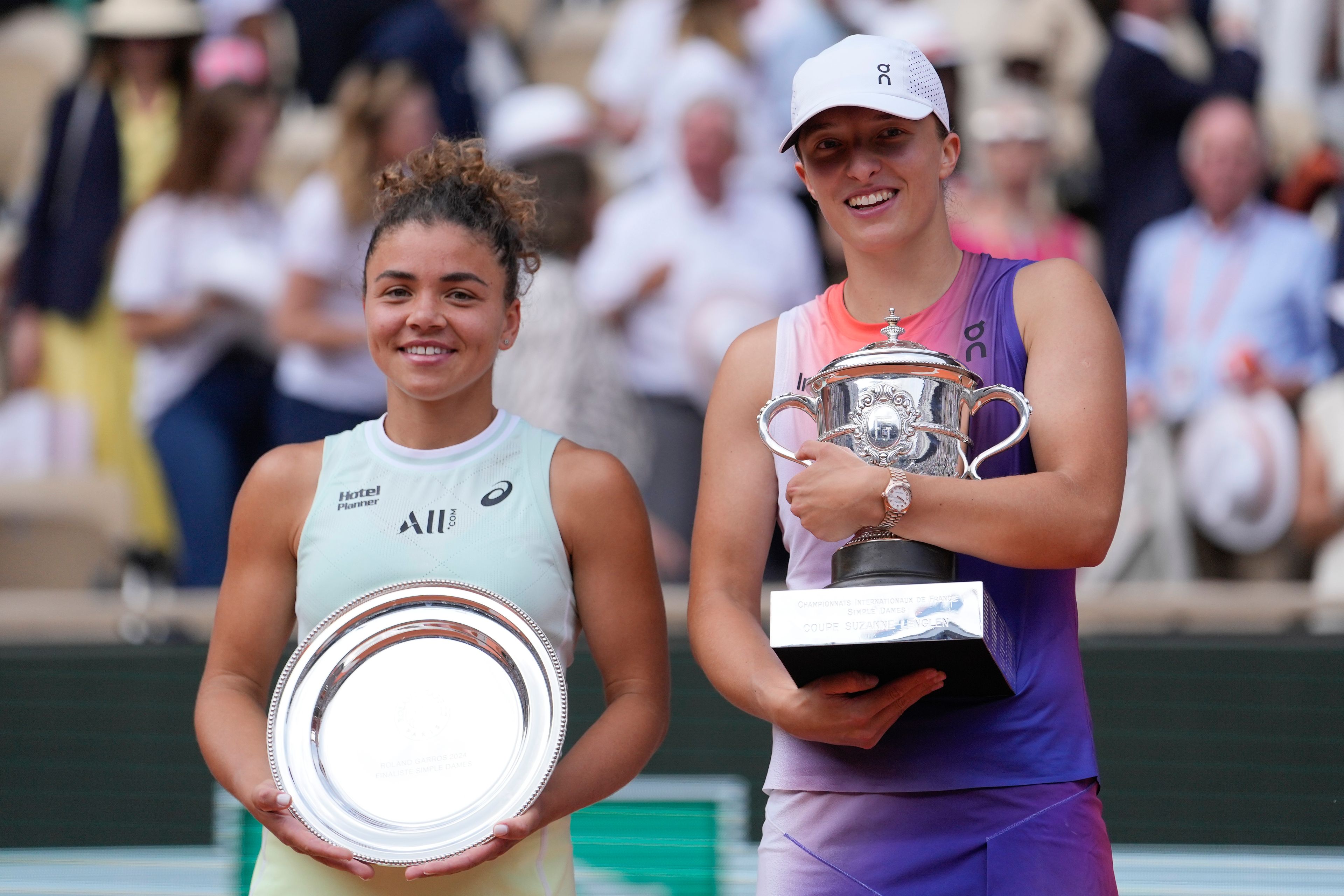 Poland's Iga Swiatek, right, holds the trophy after winning the women's final of the French Open tennis tournament against Italy's Jasmine Paolini, left, at the Roland Garros stadium in Paris, France, Saturday, June 8, 2024.