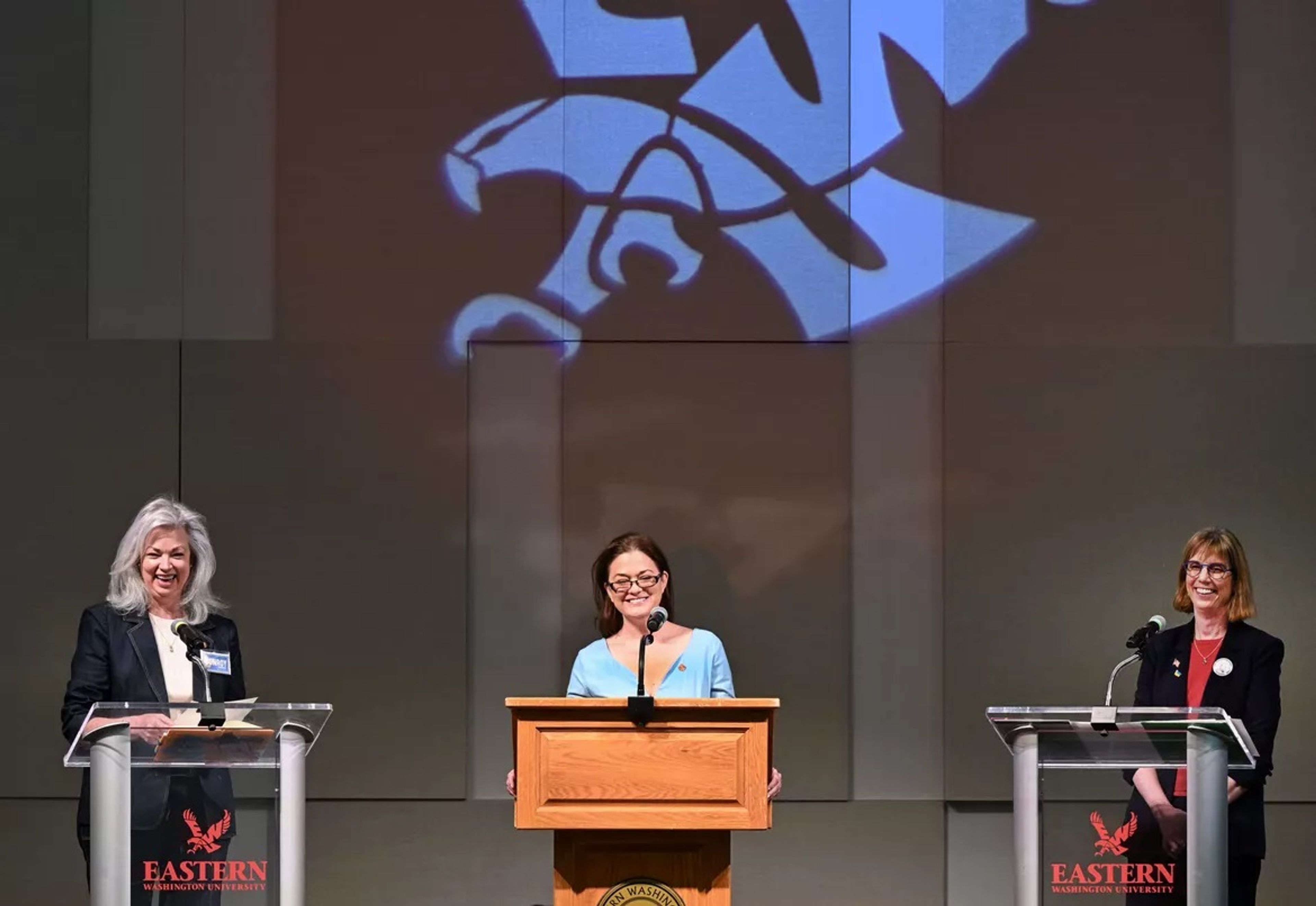 Three Democrats running for Congress in Eastern Washington, from left, Carmela Conroy, Ann Marie Danimus and Bernadine Bank, share a laugh to begin the Democratic Congressional debate on March 22, at the Pence Union Building on EWU campus in Cheney. The three candidates have difference positions on whether President Biden should withdraw his re-election bid.