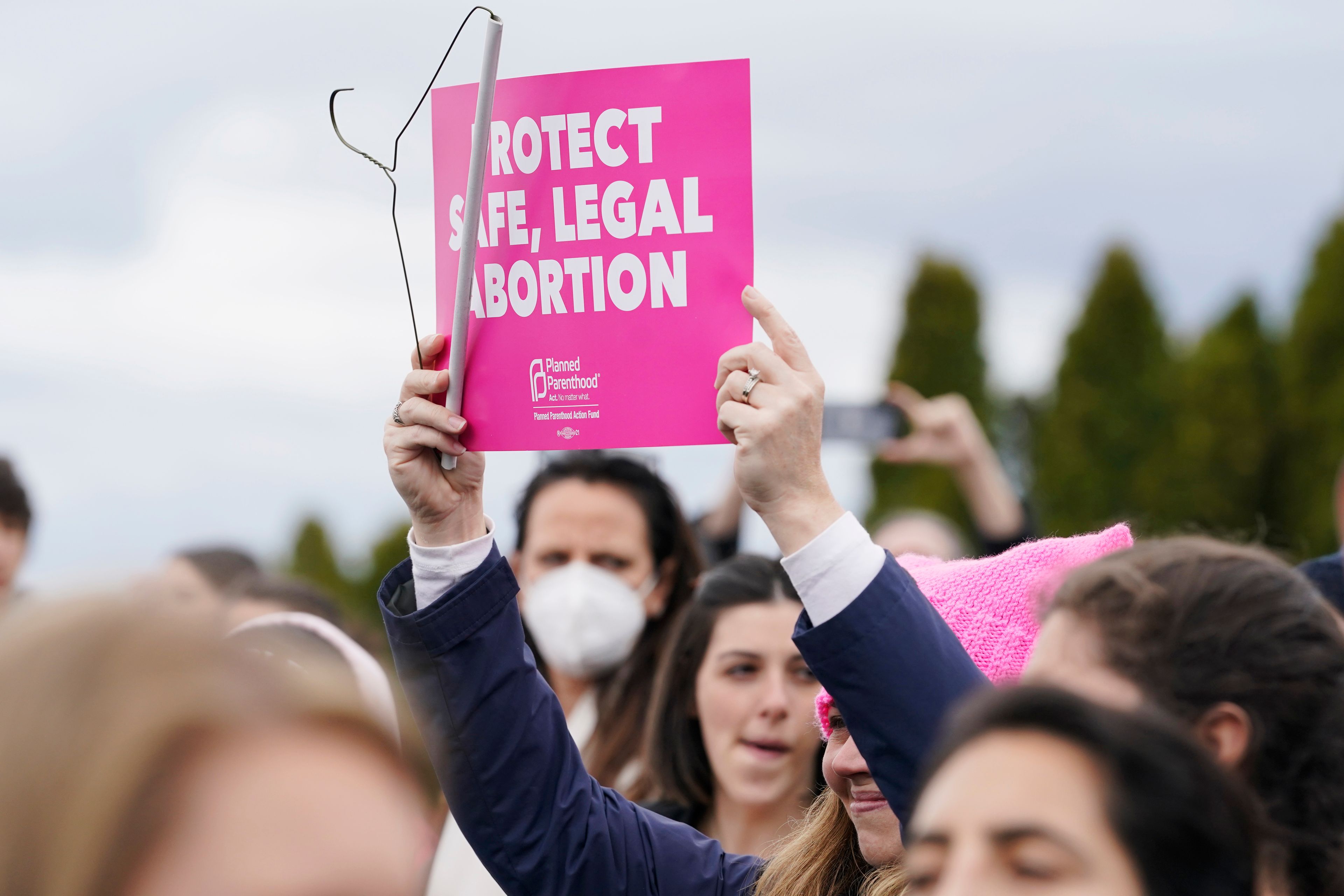 A person holds a sign that reads "Protect Safe, Legal Abortion" next to a coat hanger, Tuesday, May 3, 2022, during a rally at a park in Seattle in support of abortion rights. (AP Photo/Ted S. Warren)