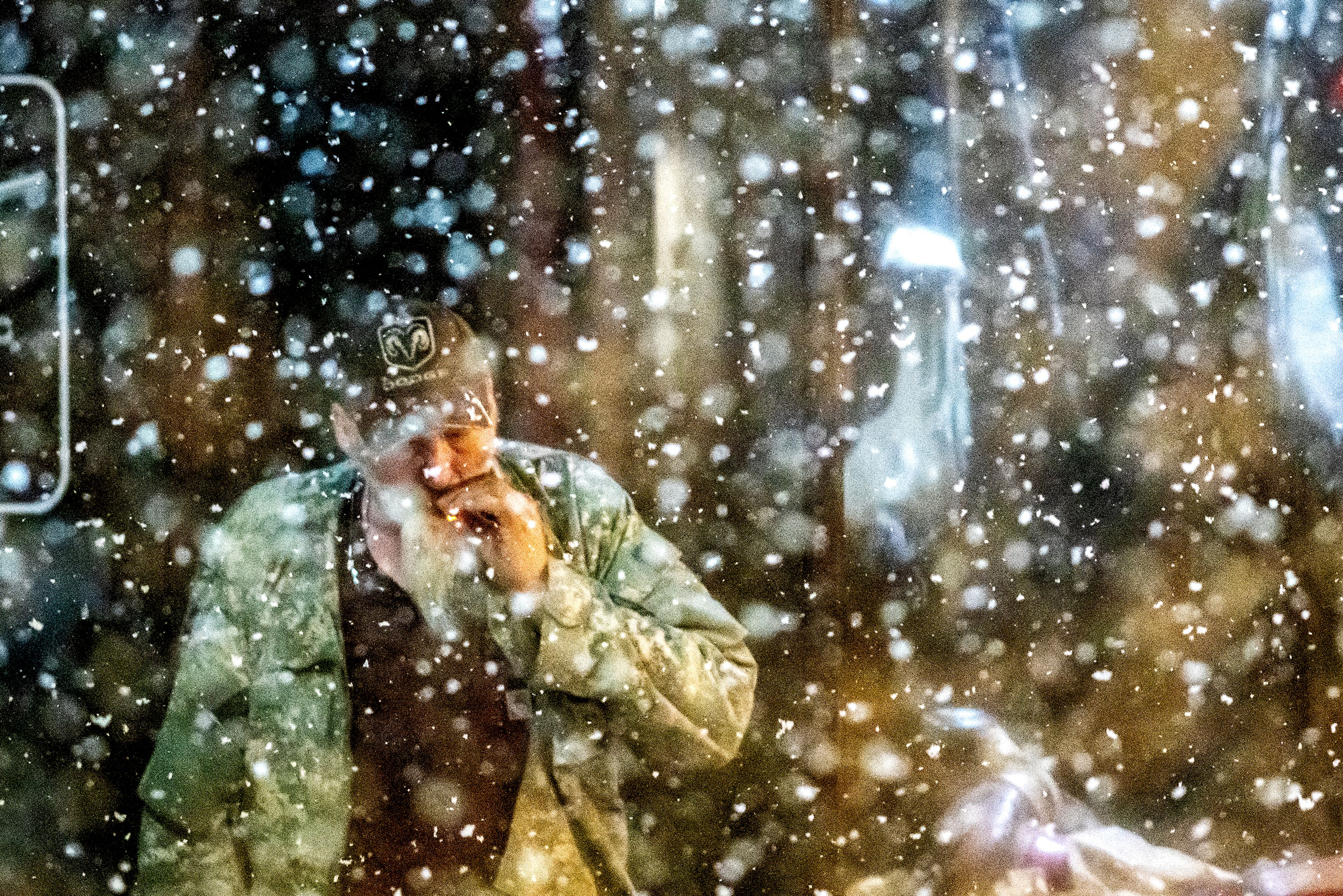 A man smokes a cigarette on Main Street as snow falls Thursday night in Lewiston.