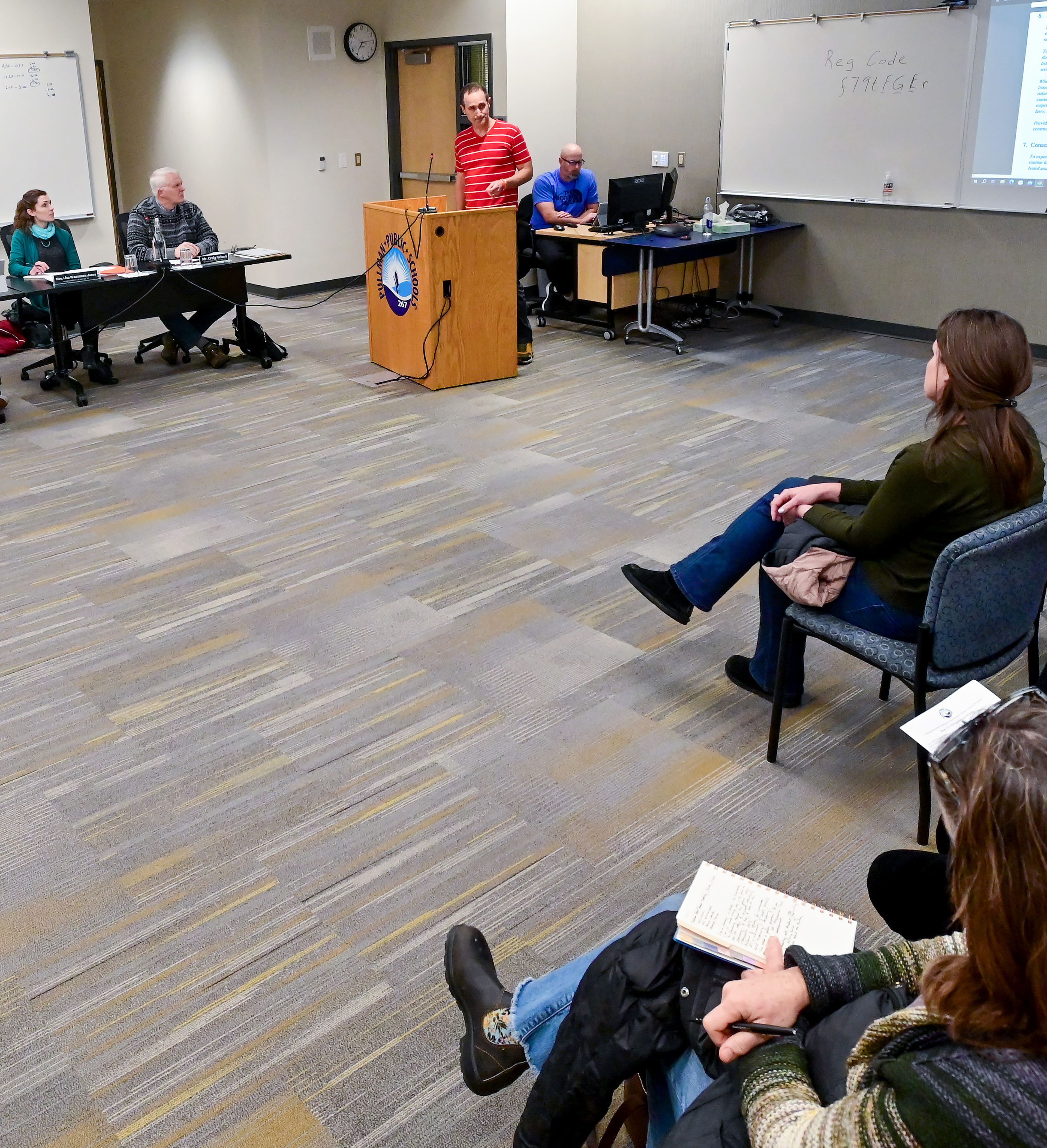 Members of the Pullman Public Schools administration and the Board of Directors listen as Anthony Haynes, center, a fifth grade teacher, speaks during public comment at a meeting on Wednesday.