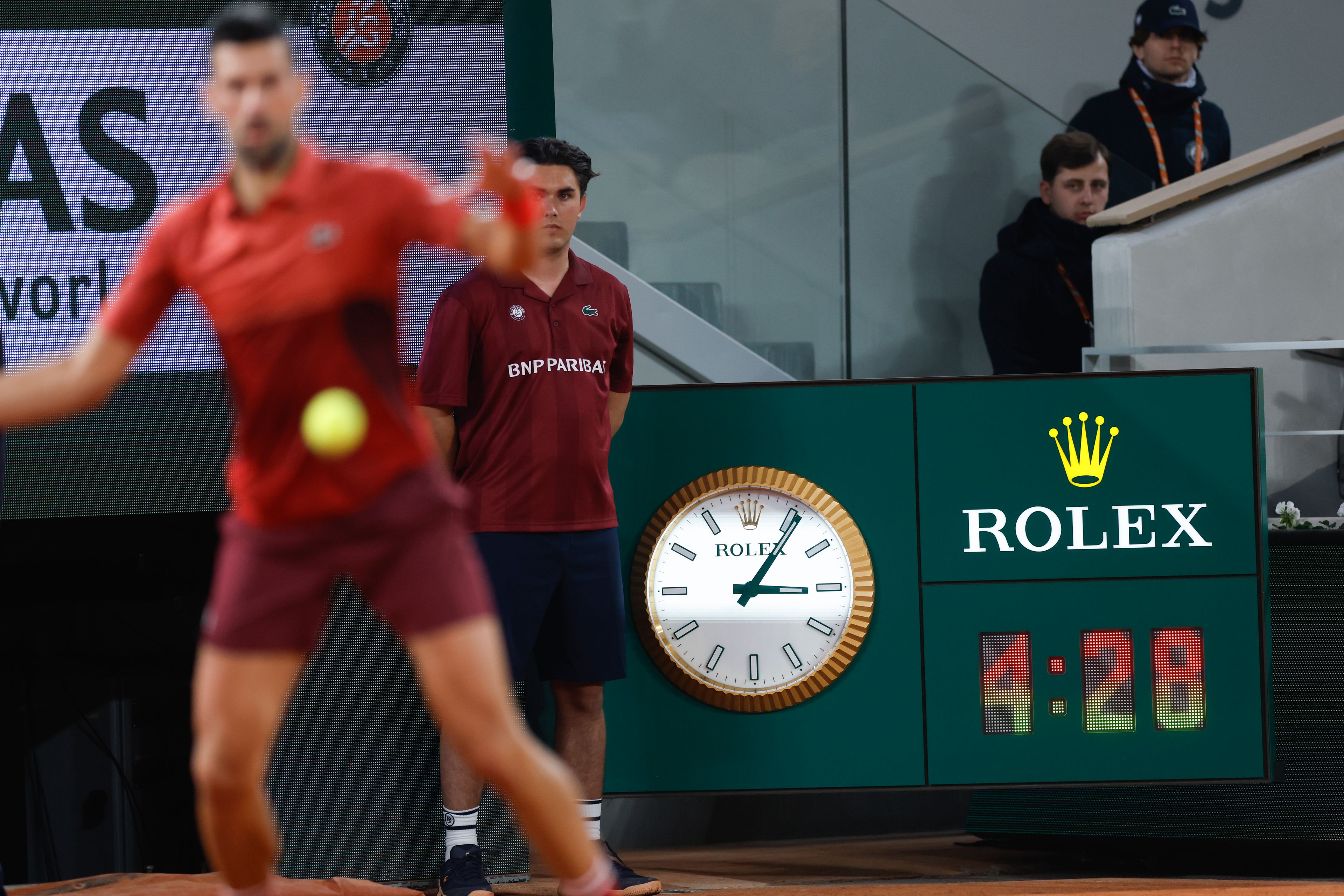 Serbia's Novak Djokovic plays a shot against Italy's Lorenzo Musetti as the clock indicates the match time played in the fifth set of their third round match of the French Open tennis tournament at the Roland Garros stadium in Paris, Sunday, June 2, 2024.