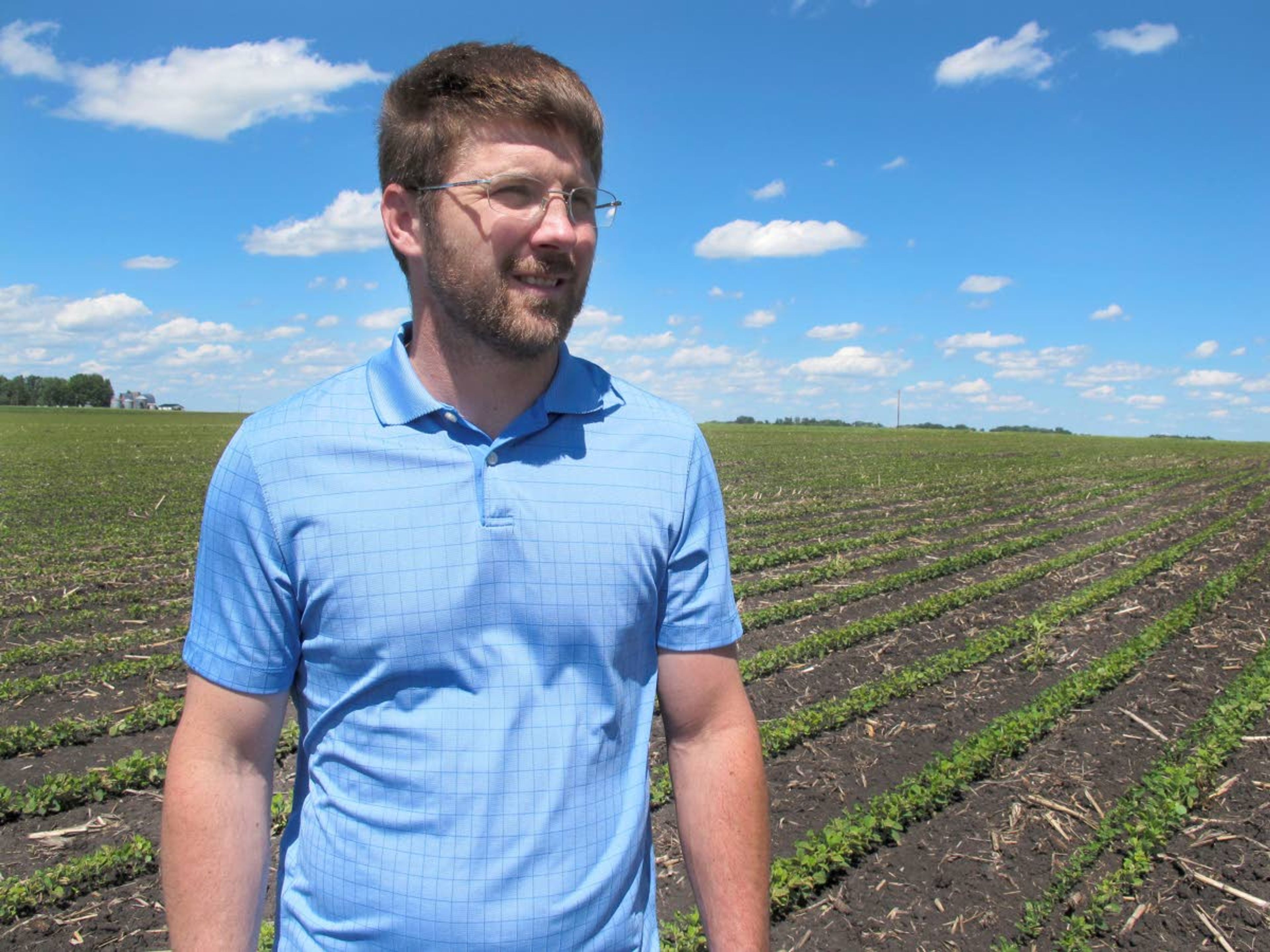 ADVANCE FOR USE WEDNESDAY, JULY 3, 2019, AT 3:01 A.M. EDT AND THEREAFTER - In this Tuesday, June 25, 2019, photo, farmer Matthew Keller walks in his soybean field near Kenyon, Minn. When the Trump administration announced a $12 billion aid package for farmers struggling under the financial strain of his trade dispute with China, the payments were capped. But records obtained by The Associated Press under the Freedom of Information Act show that many large farming operations easily found legal ways around the limits to collect big checks. Recipients who spoke to AP defended the payouts, saying they didn't even cover their losses under the trade war and that they were legally entitled to them. Keller, a pork producer in Kenyon, who also grows crops to feed his livestock, said he "definitely appreciated" the $143,820 he collected from the program. It didn't cover all his losses but it helped with his cash flow, he said. He reached the $125,000 cap on his hogs, and the remaining money was for his soybeans and corn. (AP Photo/Jeff Baenen)