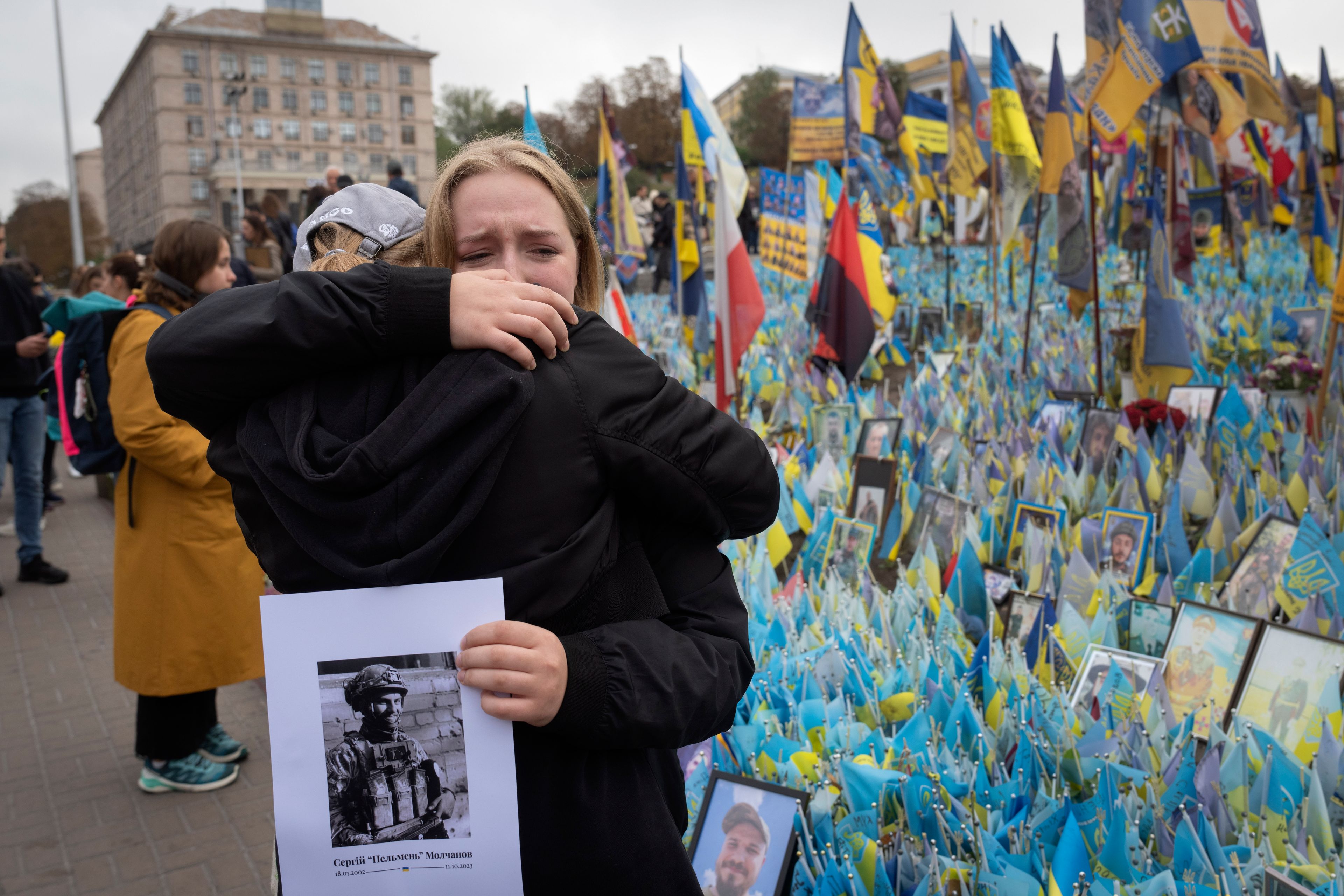 People react during a nationwide minute of silence in memory of fallen soldiers, who defended their homeland in war with Russia, on Defenders Day at the improvised war memorial in Independence square in Kyiv, Ukraine, Tuesday, Oct. 1, 2024. (AP Photo/Efrem Lukatsky)