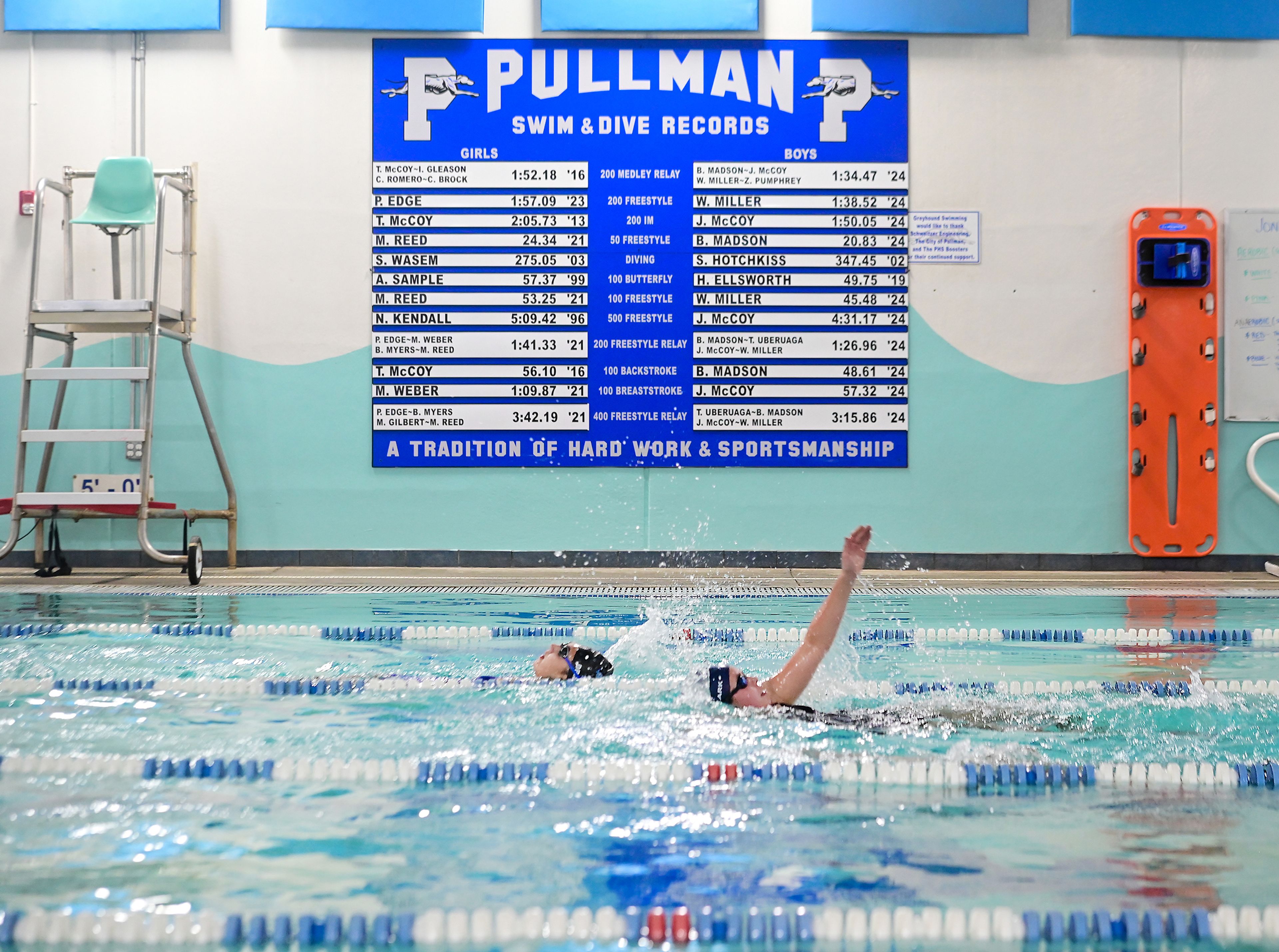 A record board hangs above the lap pool Thursday at the Pullman Aquatic & Fitness Center as members of the Pullman High School swim team practice.