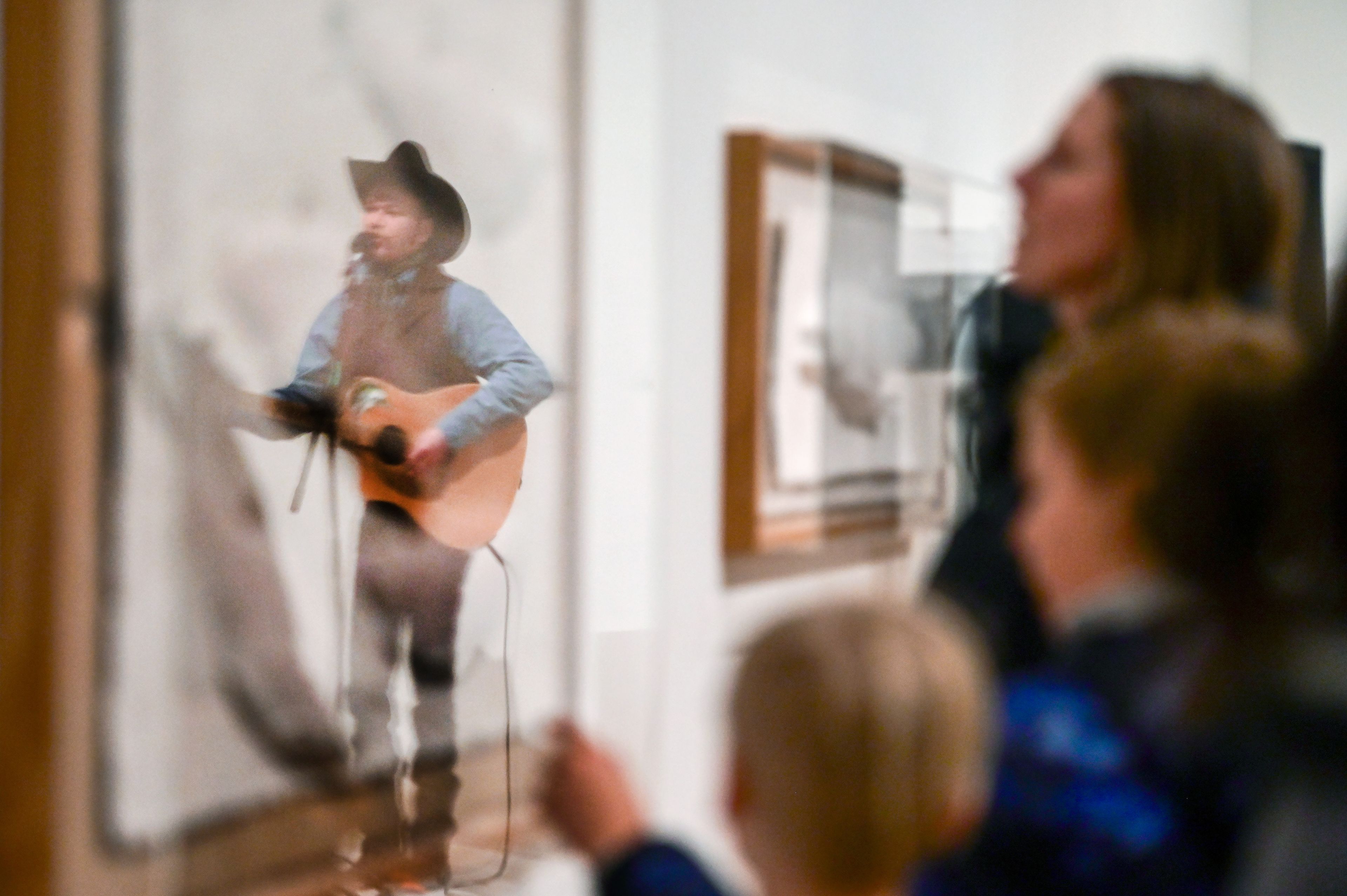 Blaine Andrew Ross is reflected in the artwork of Lonnie Hutson while performing at the closing concert for Moscow Contemporary as part of its Art Walk series in Moscow on Thursday.