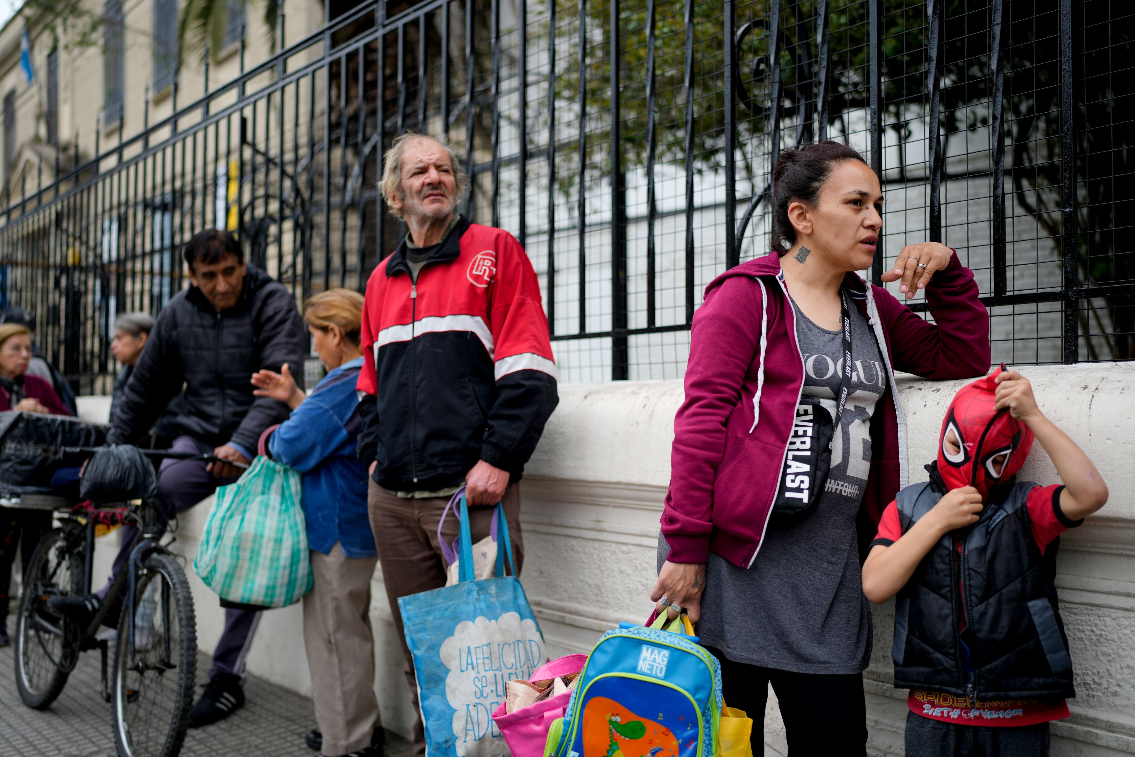 Sofia Gonzalez Figueroa and her son Emanuel stand in line outside a soup kitchen for a free, hot meal, where they walked to from home on the outskirts of Buenos Aires, Argentina, Monday, Sept. 9, 2024. (AP Photo/Natacha Pisarenko)