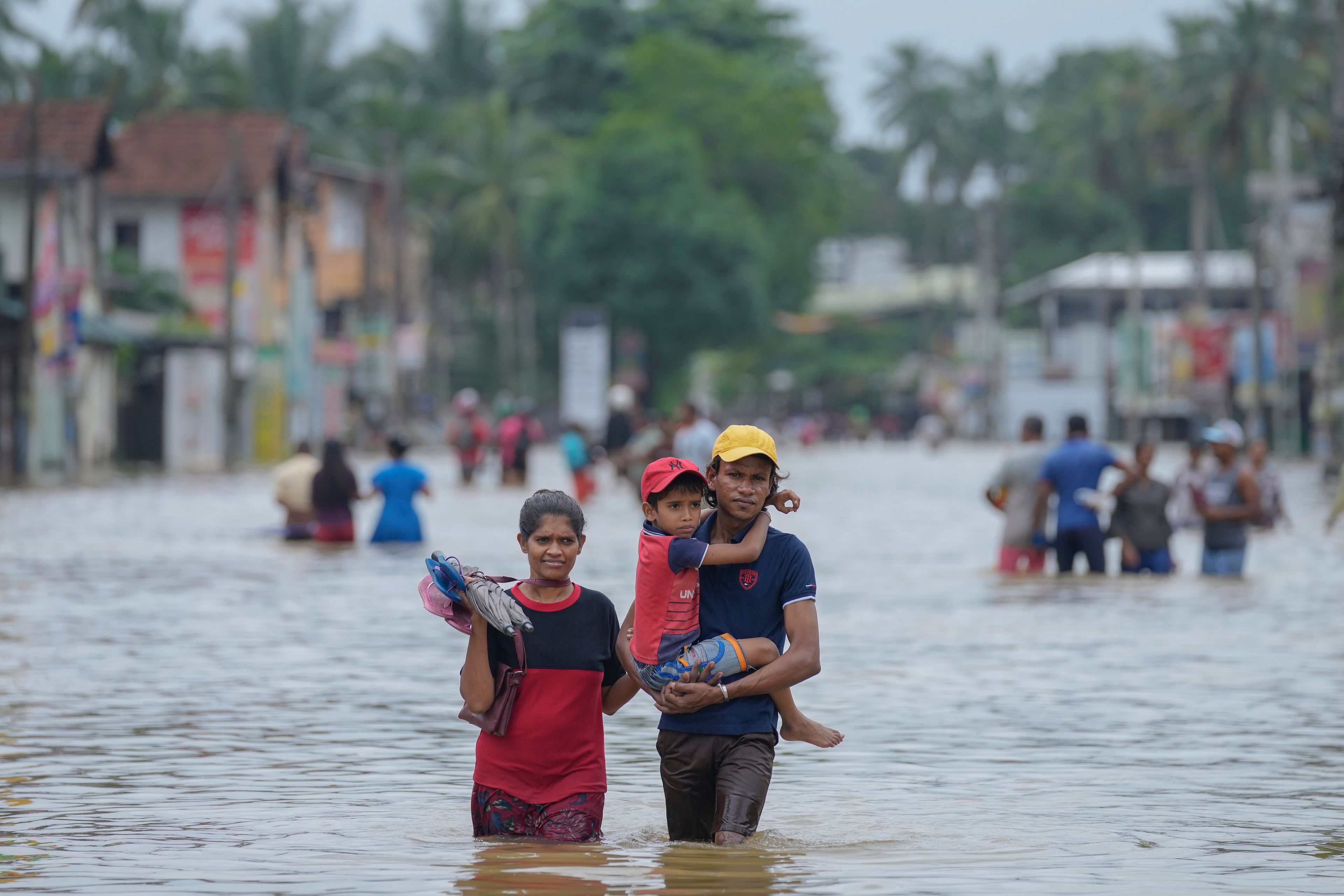 People wade through a flooded street in Biyagama, a suburb of Colombo, Sri Lanka, Monday, Jun. 3, 2023. Sri Lanka closed schools on Monday as heavy rains triggered floods and mudslides in many parts of the island nation, killing at least 10 people while six others have gone missing, officials said.