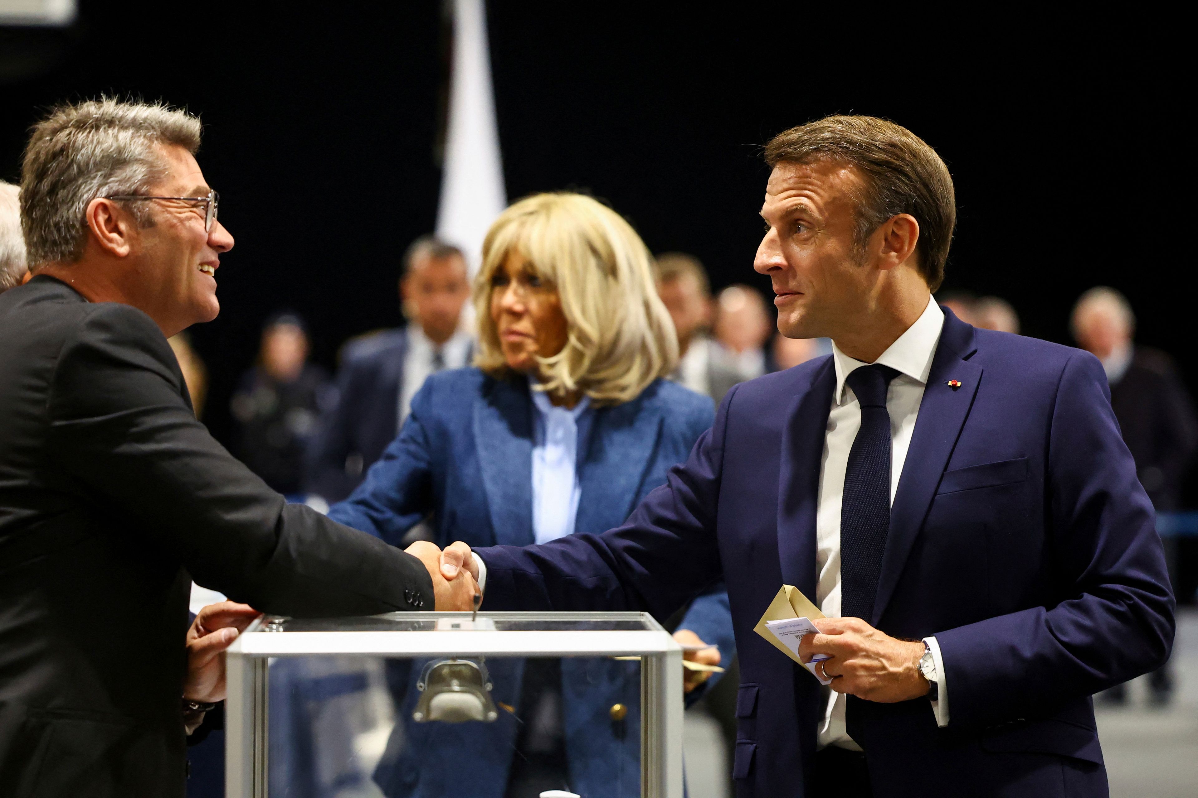 French President Emmanuel Macron, right, shakes hands with a polling station official during the European election, Sunday, June 9, 2024 in Le Touquet-Paris-Plage, northern France. Polling stations opened across Europe on Sunday as voters from 20 countries cast ballots in elections that are expected to shift the European Union's parliament to the right and could reshape the future direction of the world's biggest trading bloc.