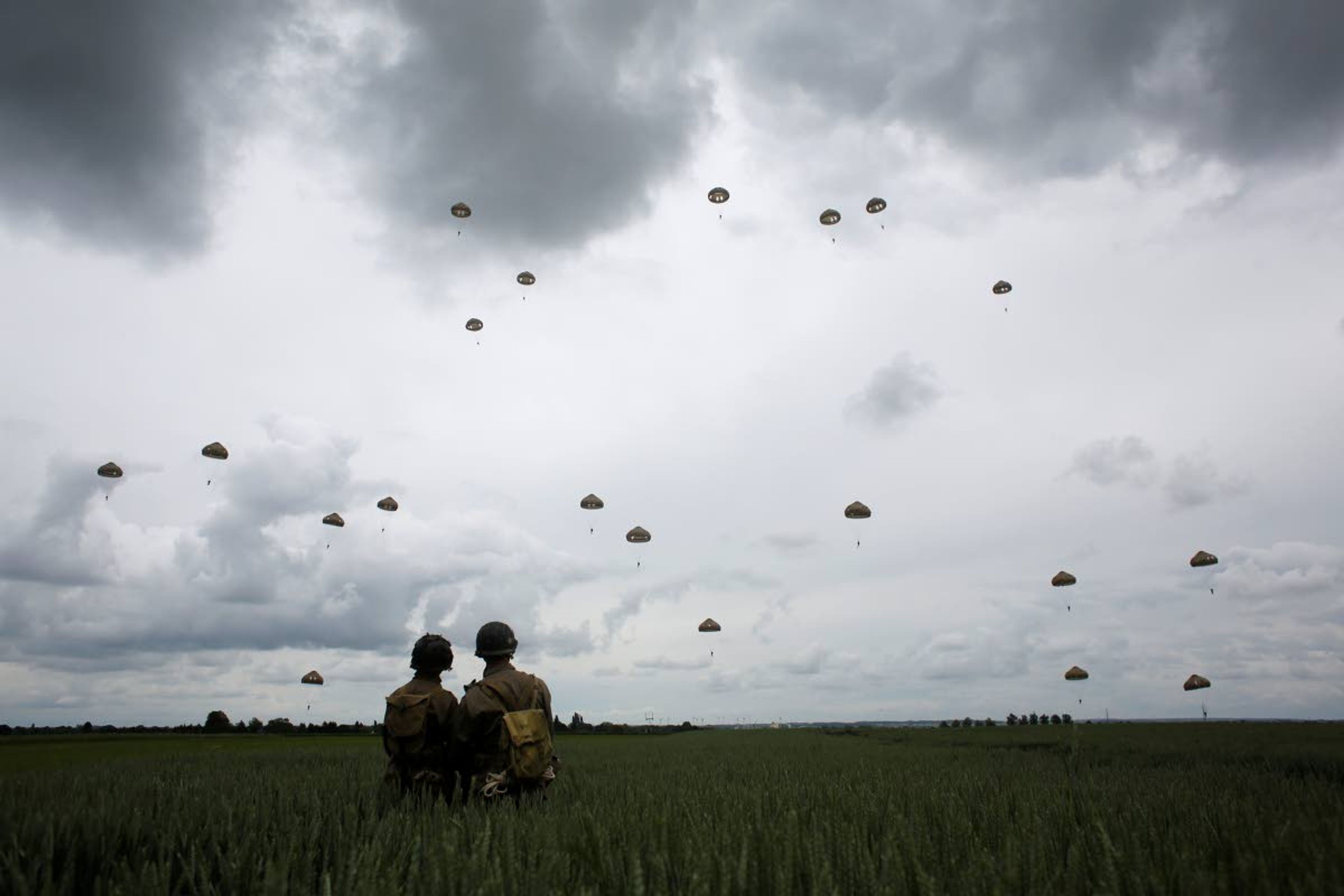 World War II enthusiasts watch French and British parachutists jumping during a commemorative parachute jump over Sannerville, Normandy, on Wednesday.