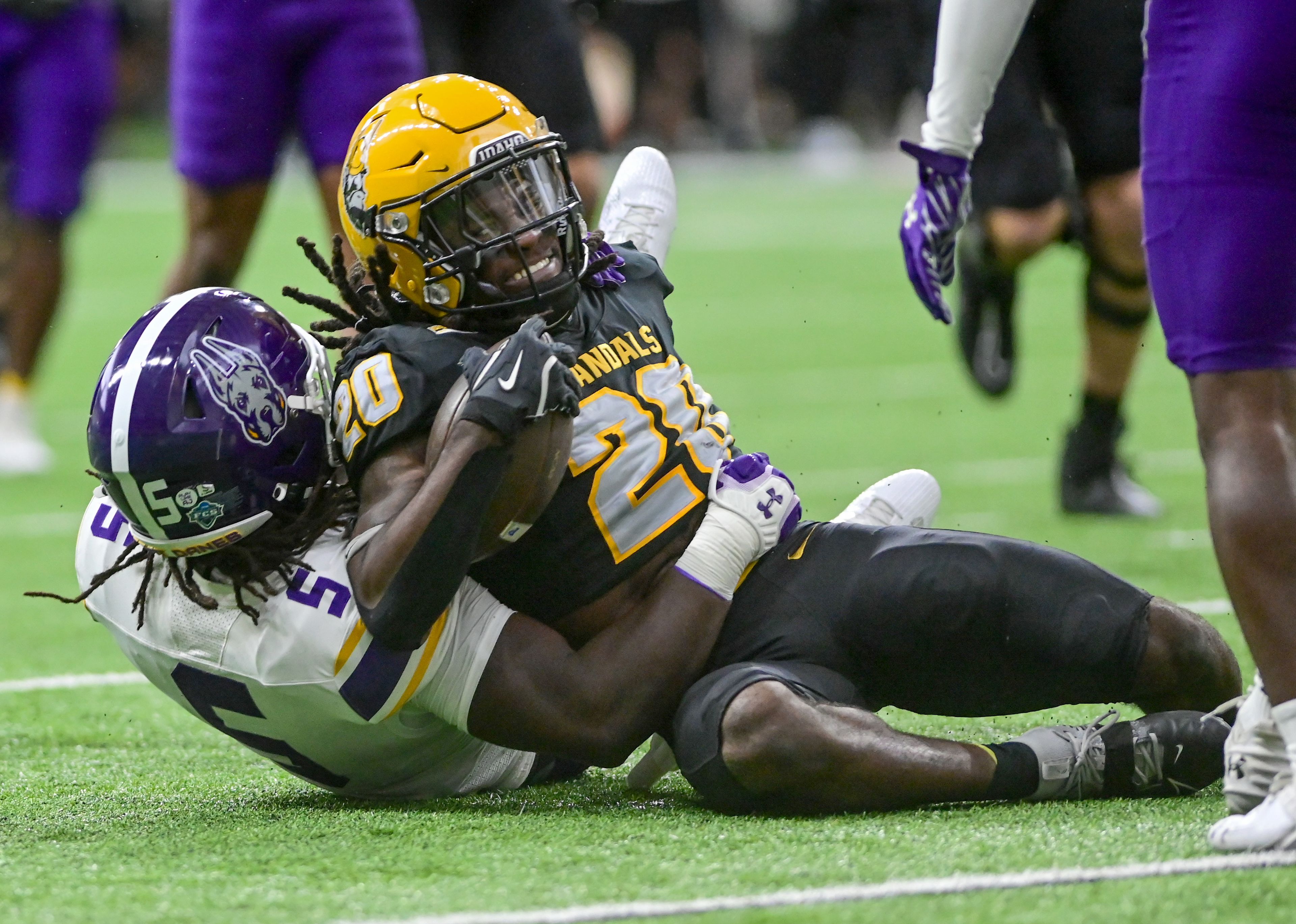 Idaho Vandals running back Elisha Cummings (20) carries the ball close to the 10-yard line before being tackled by Albany Great Danes linebacker Ron Holmes (5) Saturday at the P1FCU Kibbie Dome in Moscow.,