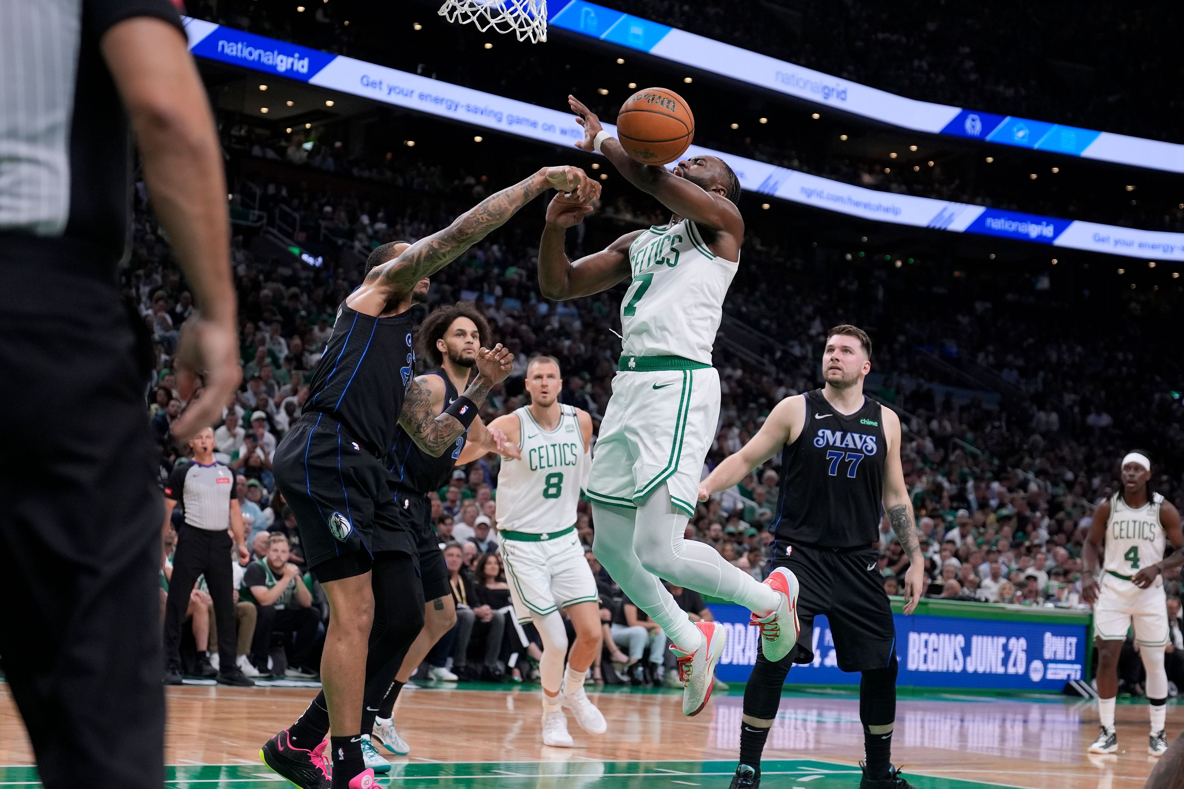 Dallas Mavericks forward P.J. Washington, left, fouls Boston Celtics guard Jaylen Brown, center, during the first half of Game 1 of basketball's NBA Finals on Thursday, June 6, 2024, in Boston.