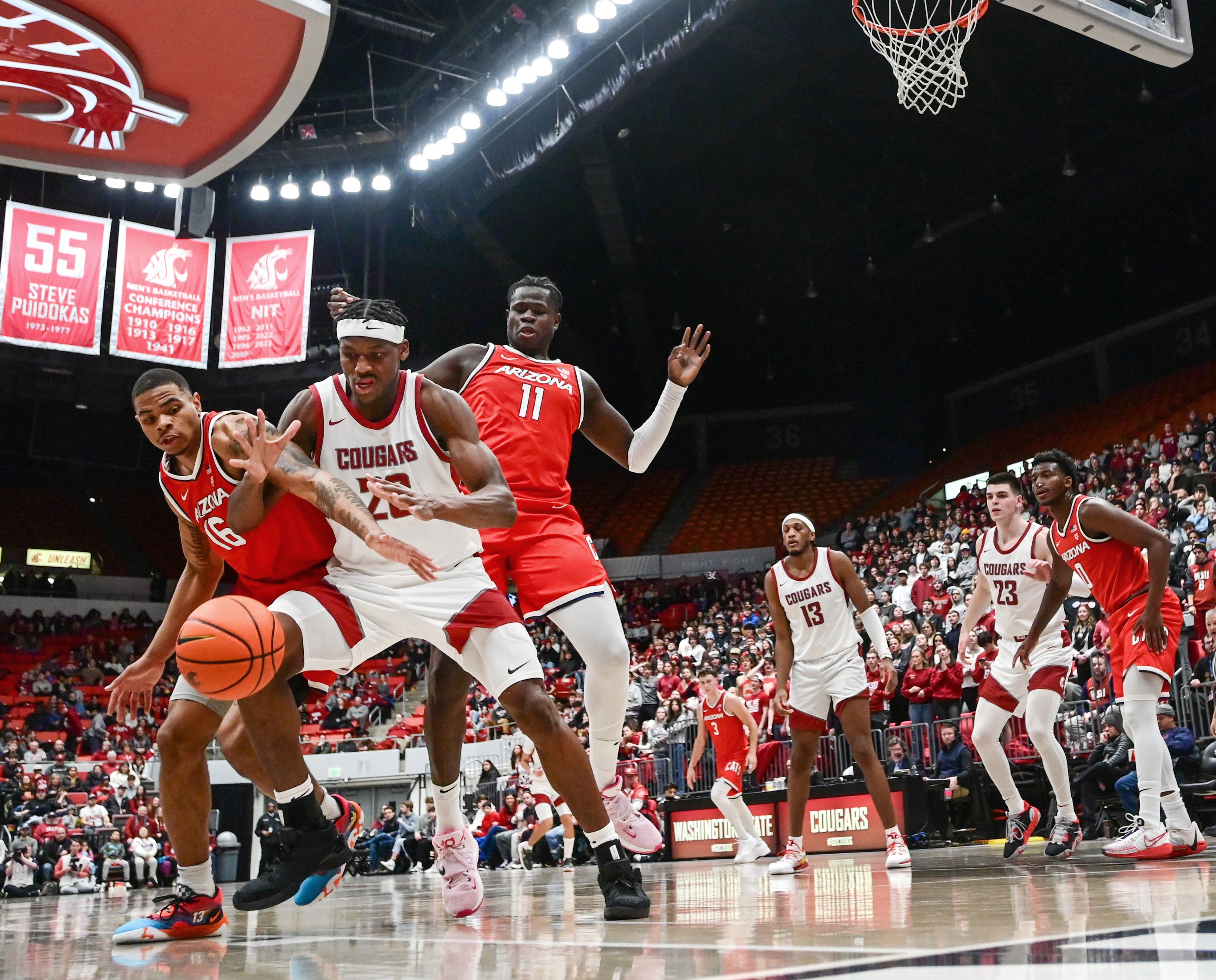 Arizona Wildcats forward Keshad Johnson (16) and Washington State Cougars center Rueben Chinyelu (20) clamor for control of a rebounding ball off the Cougars net in Pullman on Saturday.